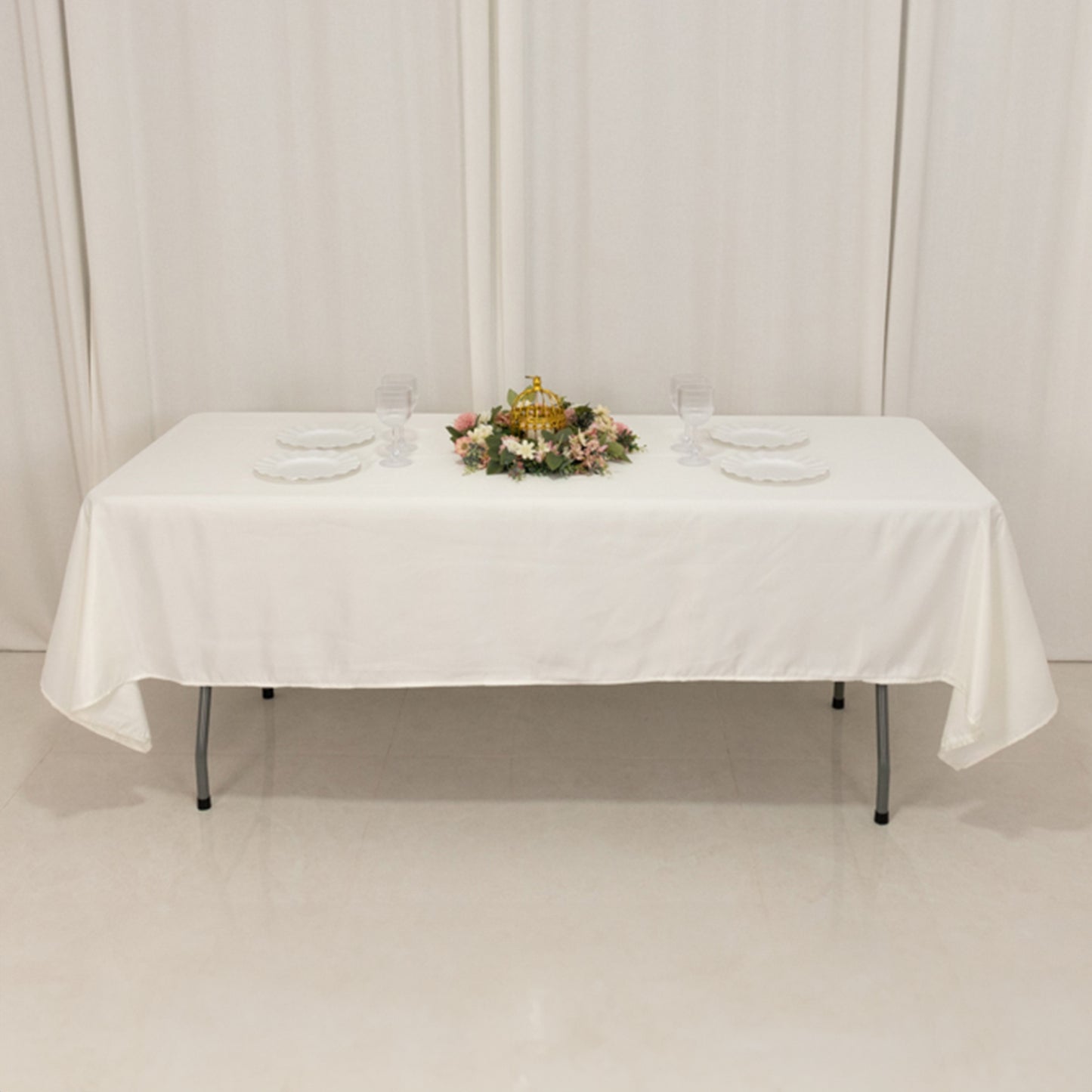Ivory satin rectangle tablecloth on a dining table with floral centerpiece.