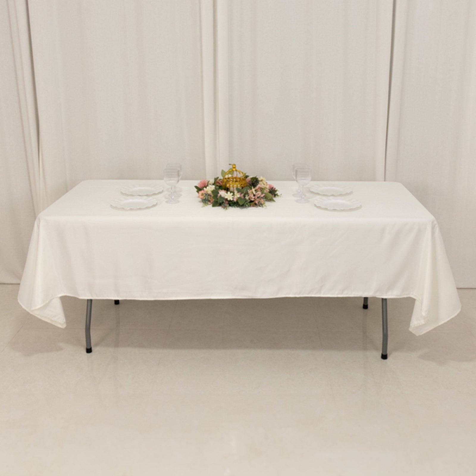 Ivory satin rectangle tablecloth on a dining table with floral centerpiece.
