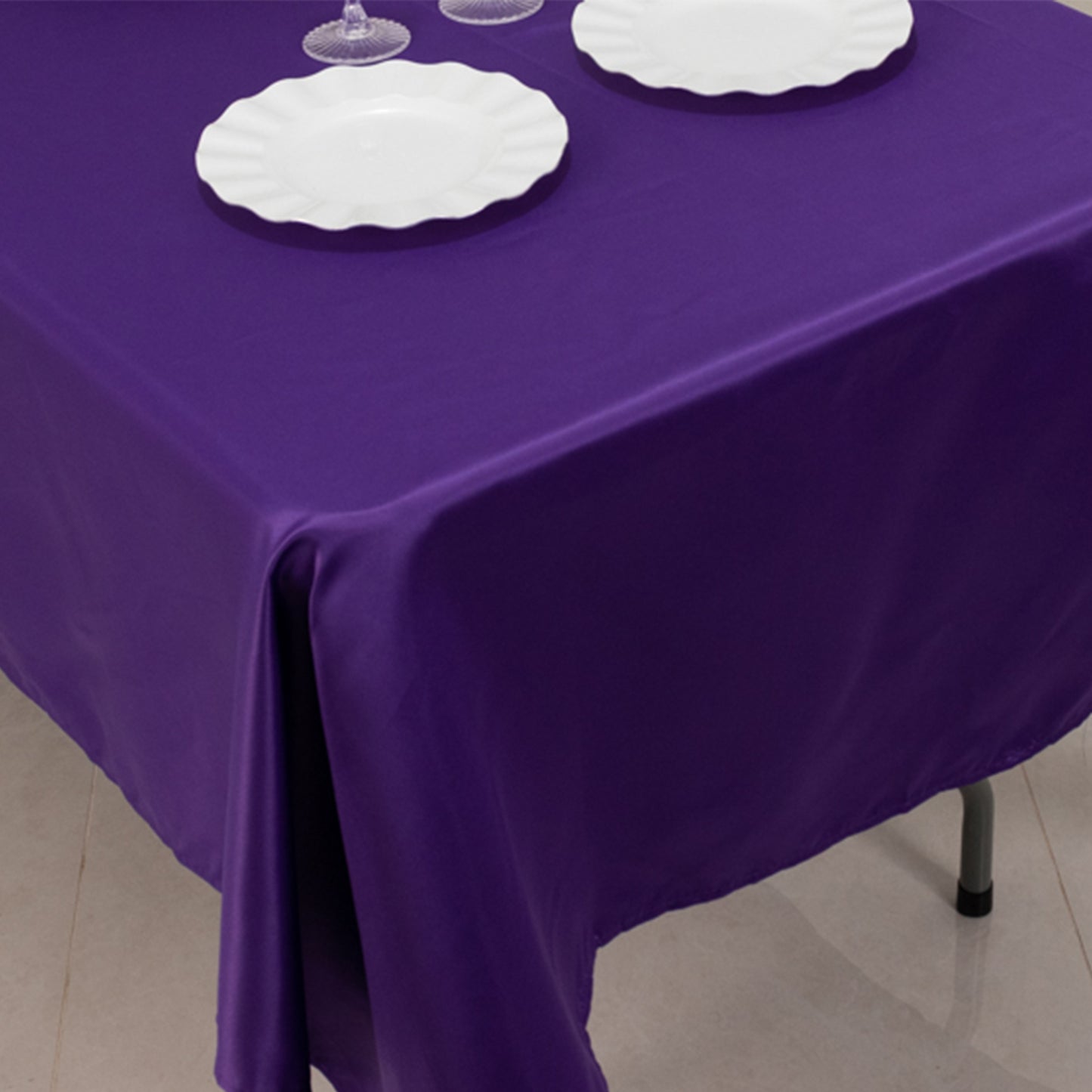 Purple satin tablecloth on a dining table with white plates.