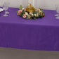 Purple rectangular tablecloth on a table with floral decor and glassware.