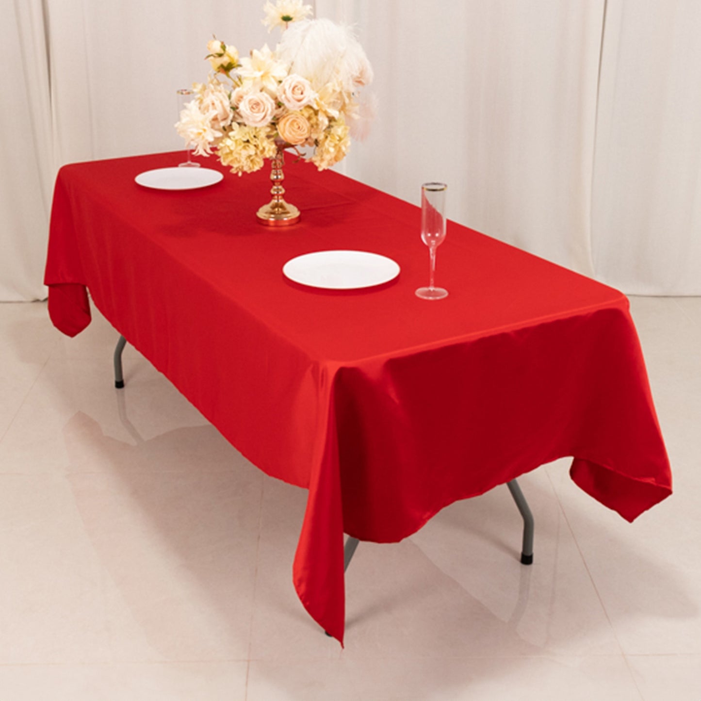 Red satin rectangle tablecloth on a table with a floral centerpiece.