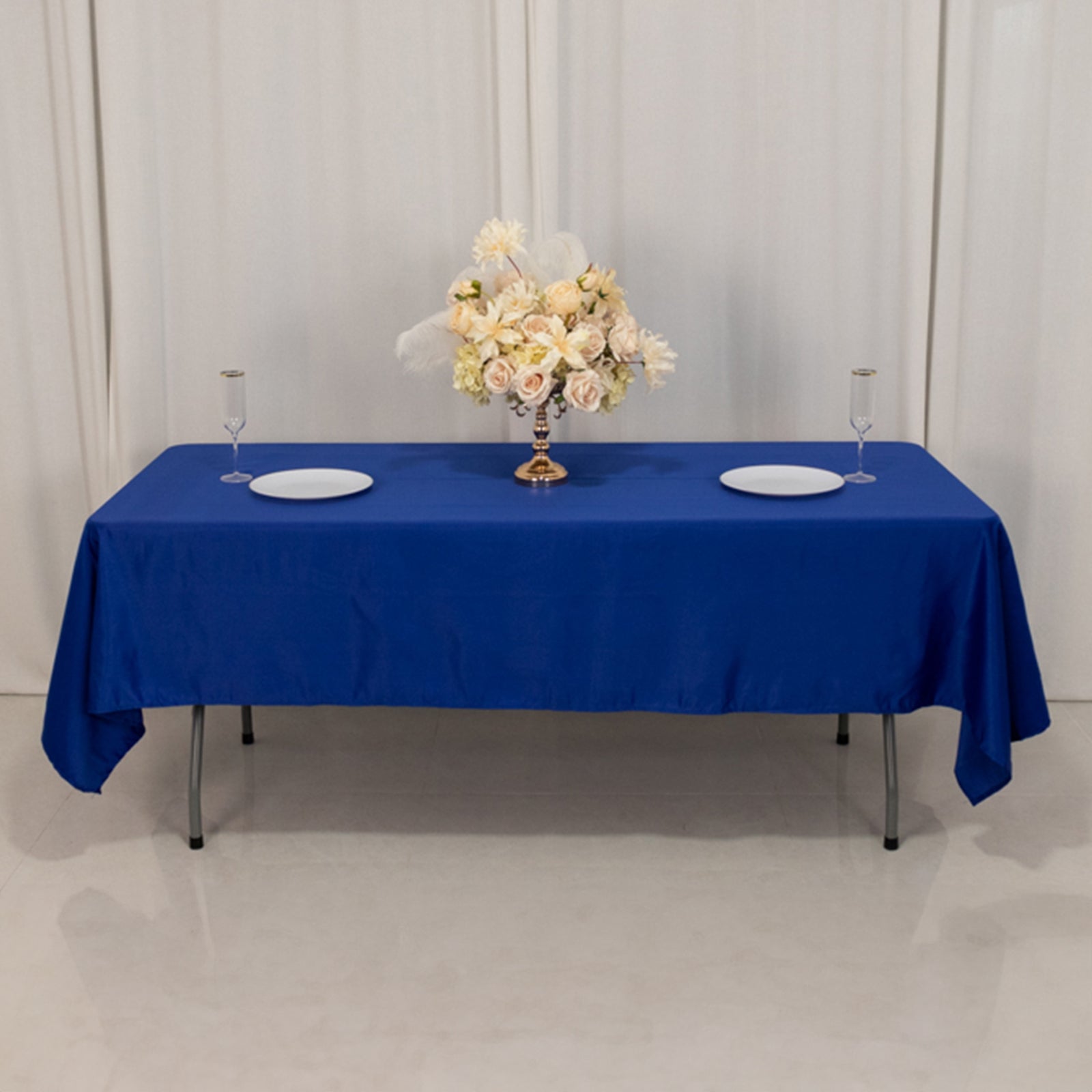 Royal blue satin rectangle tablecloth with floral centerpiece on a table.