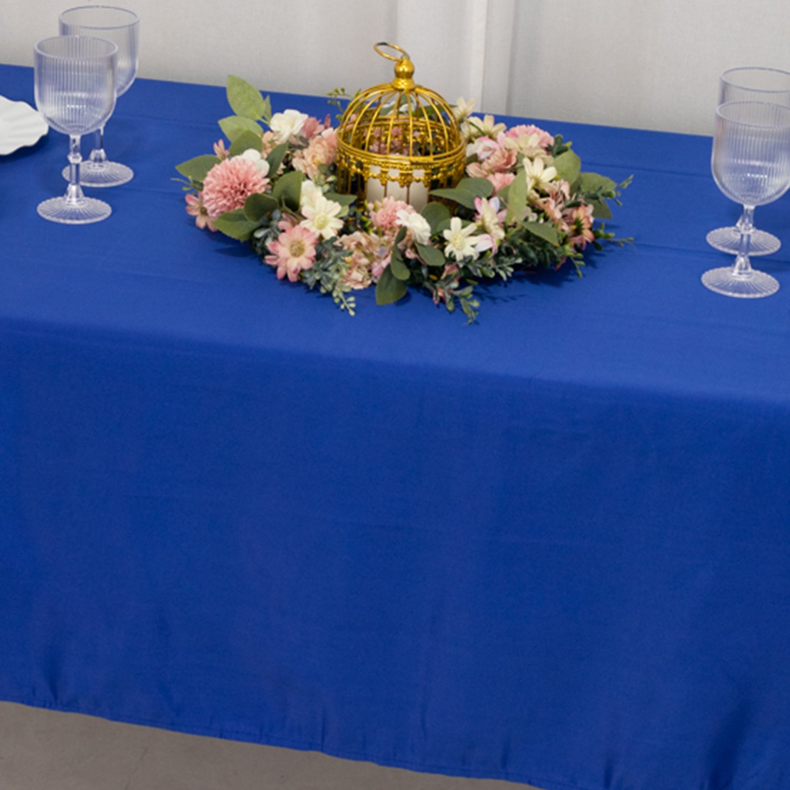 Royal blue rectangular tablecloth on a decorated table with floral arrangement.