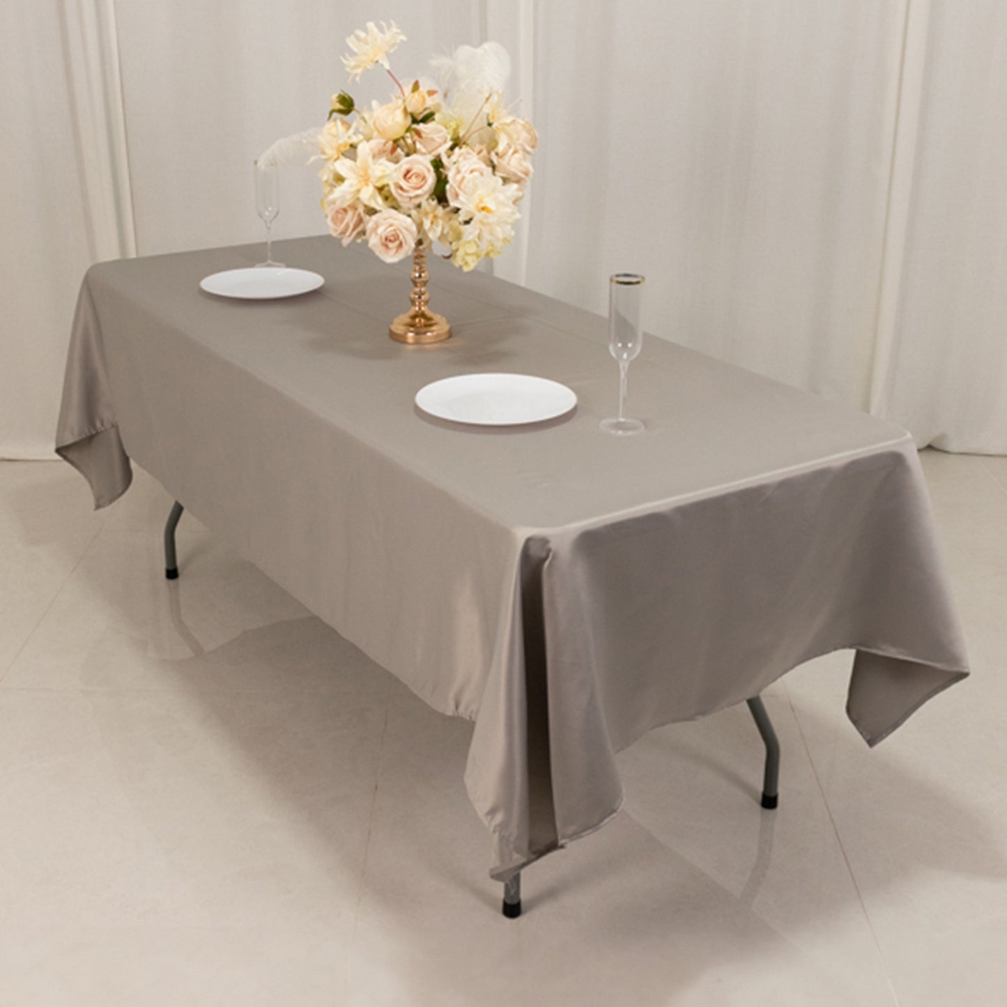 Silver satin tablecloth on a rectangular table with floral arrangement.