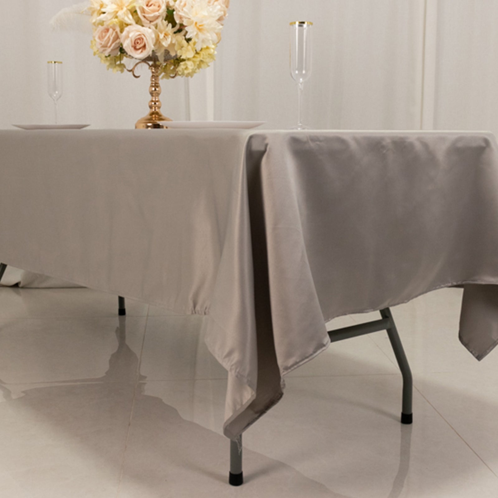 Silver satin rectangle tablecloth on a dining table with floral centerpiece.