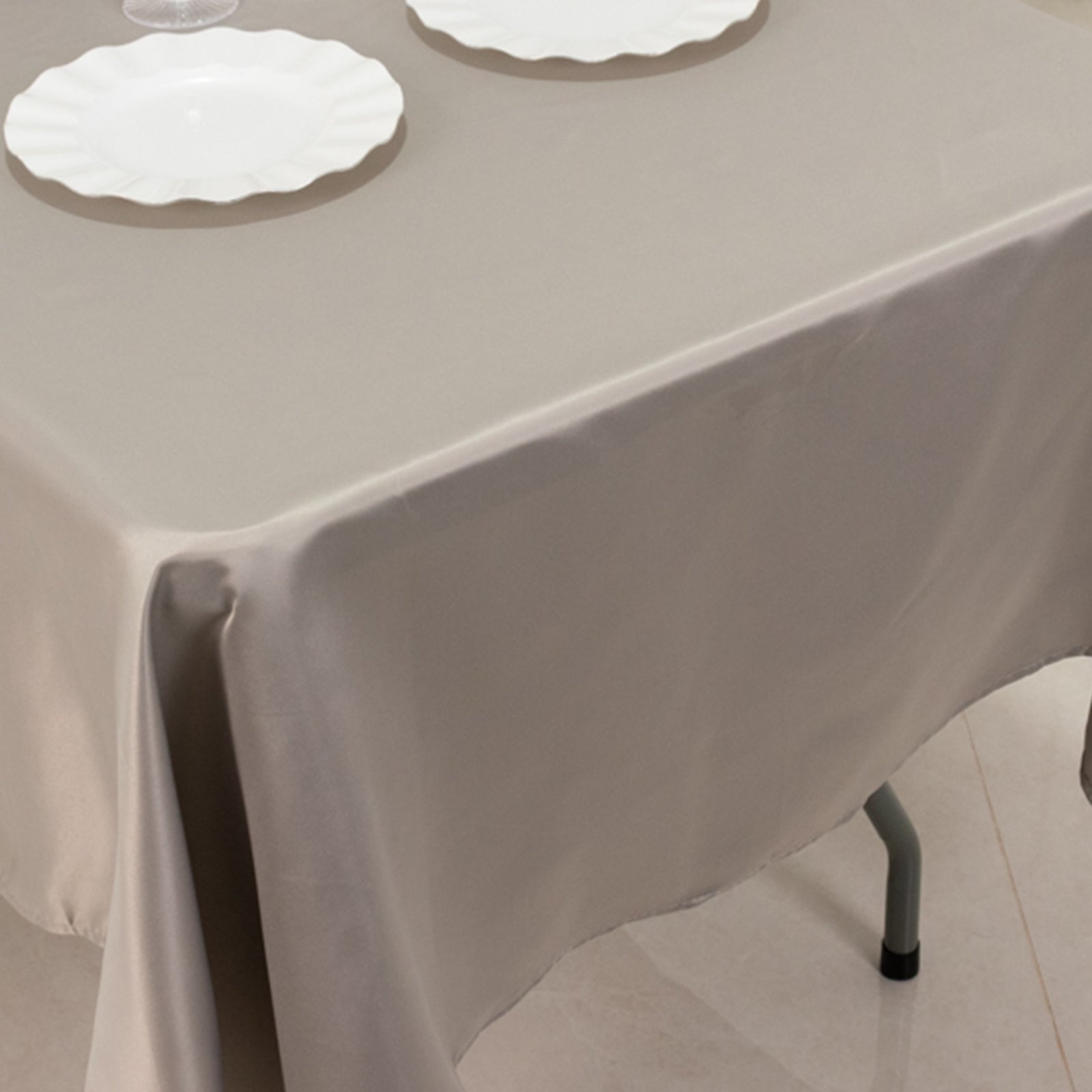 Silver satin rectangle tablecloth on a table with white plates.