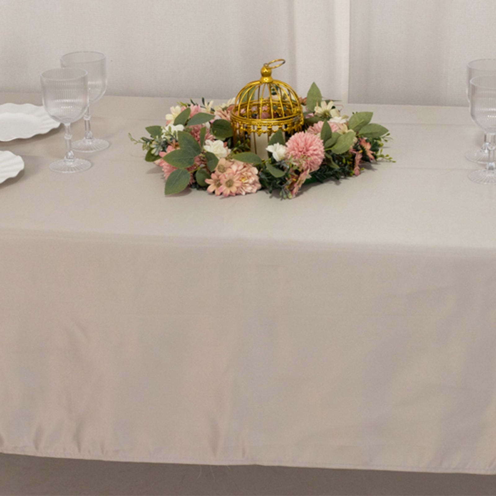 Silver rectangle tablecloth on a dining table with floral centerpiece.