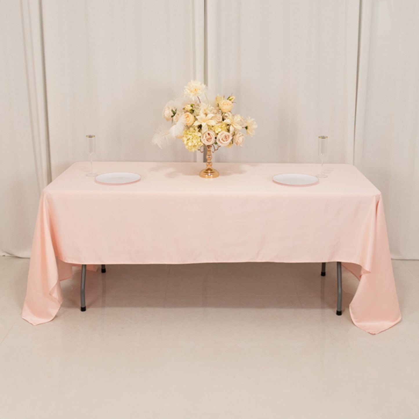 Blush satin rectangle tablecloth on a table with floral arrangement.