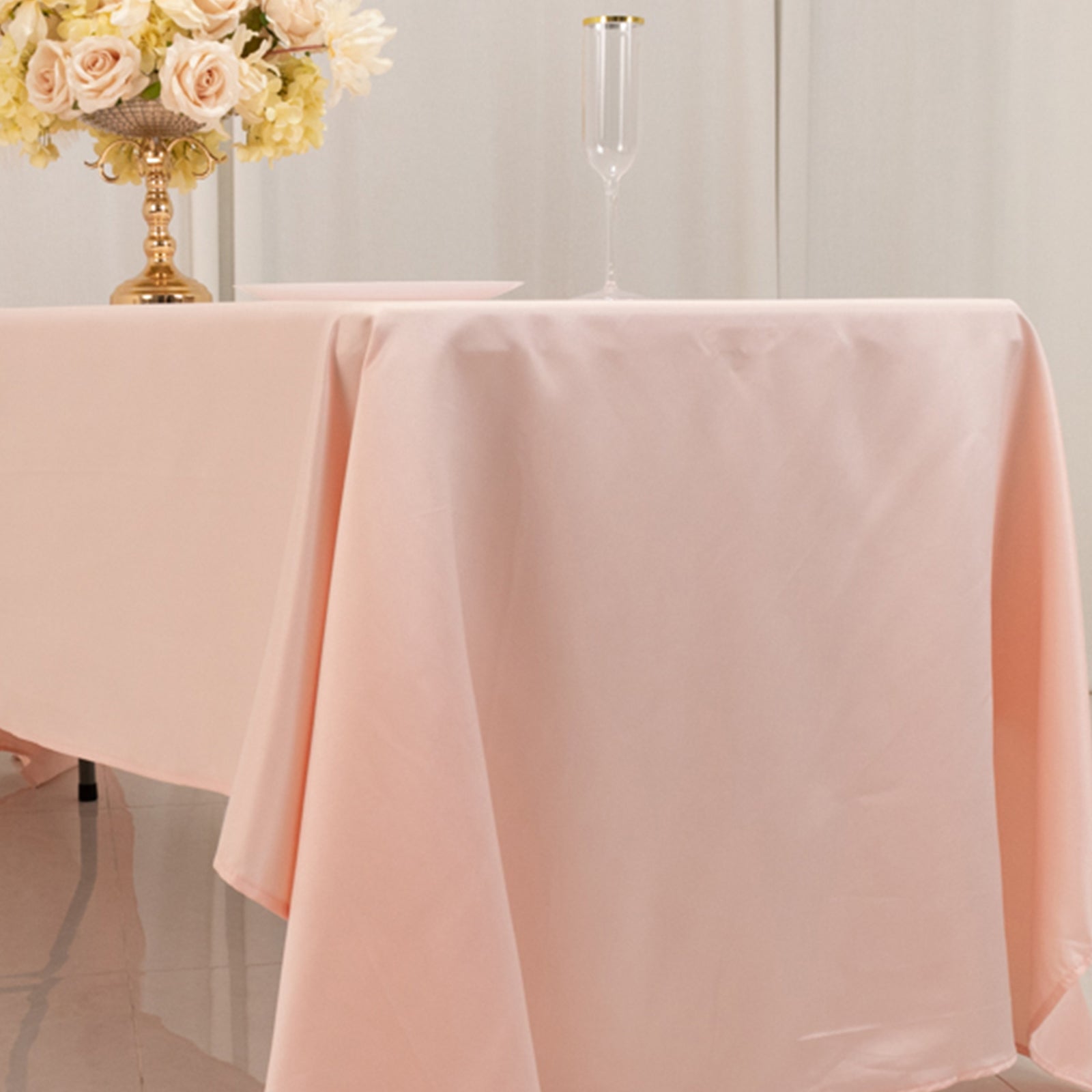 Blush satin rectangle tablecloth on a dining table with floral centerpiece.
