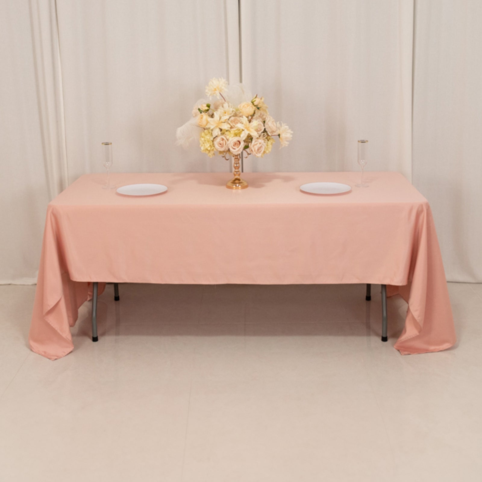 Dusty rose satin rectangle tablecloth on a table with floral centerpiece.