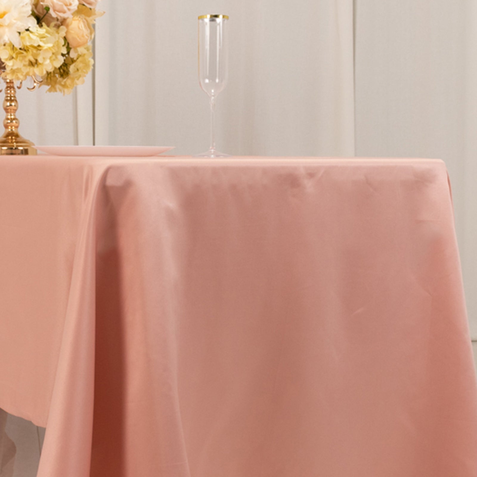 Dusty rose satin rectangle tablecloth on a dining table.