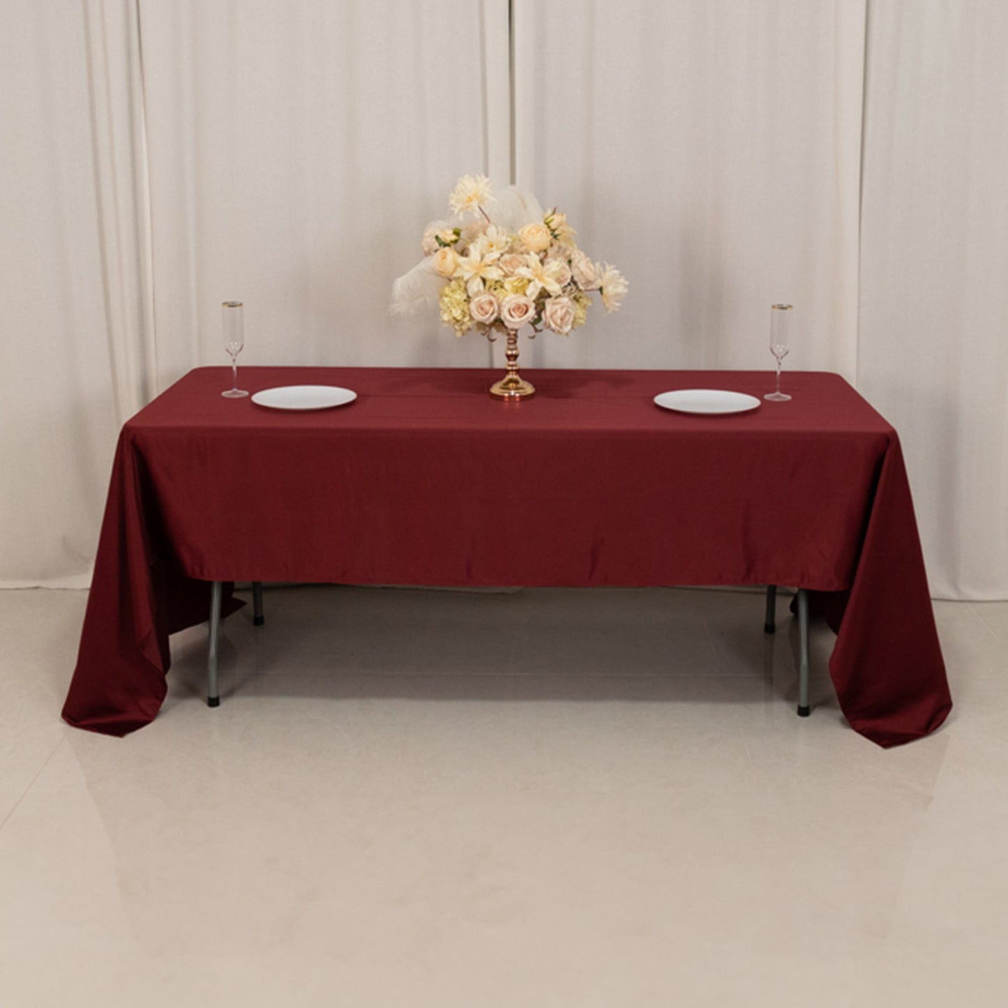 Burgundy satin rectangle tablecloth on a dining table with floral centerpiece.