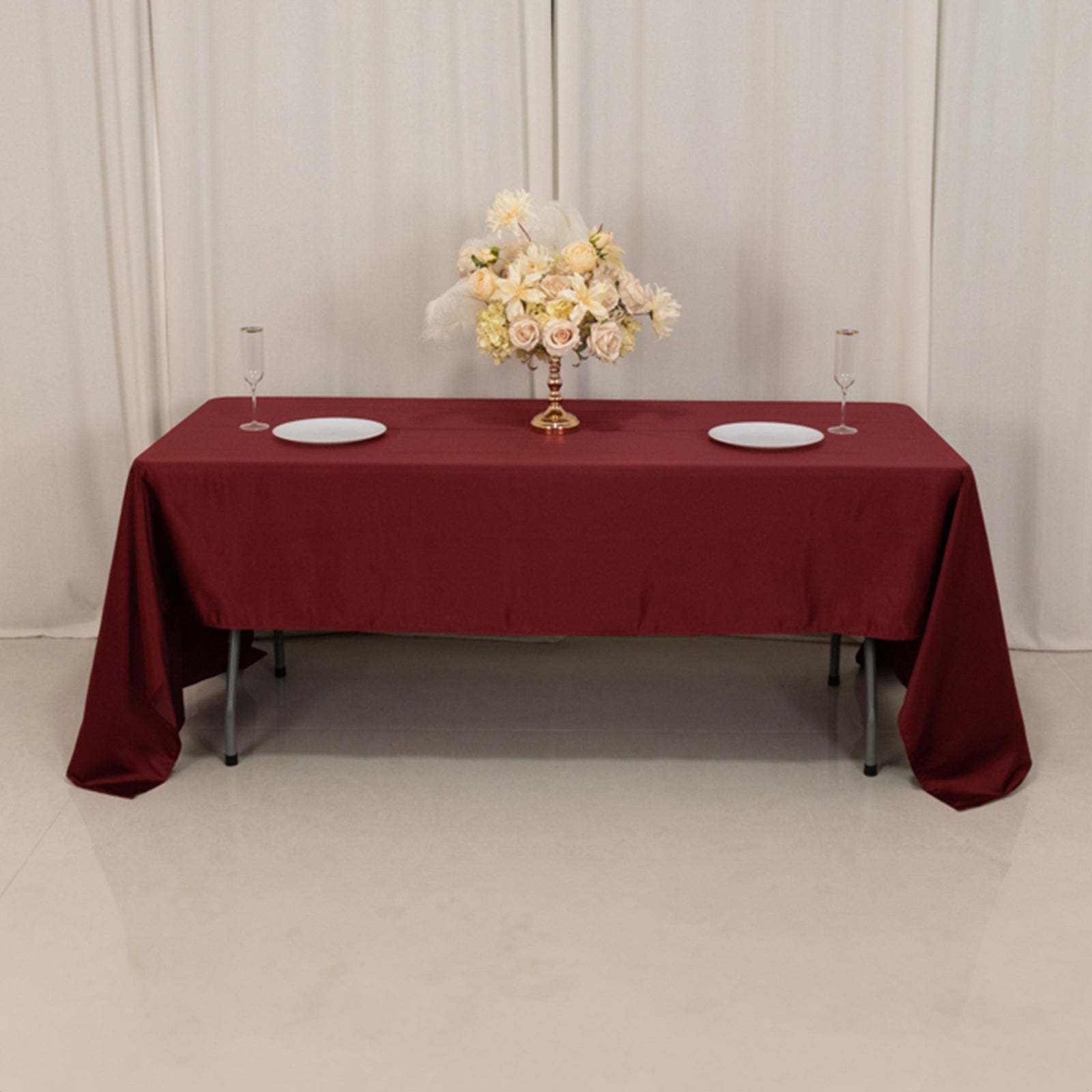 Burgundy satin rectangle tablecloth on a dining table with floral centerpiece.