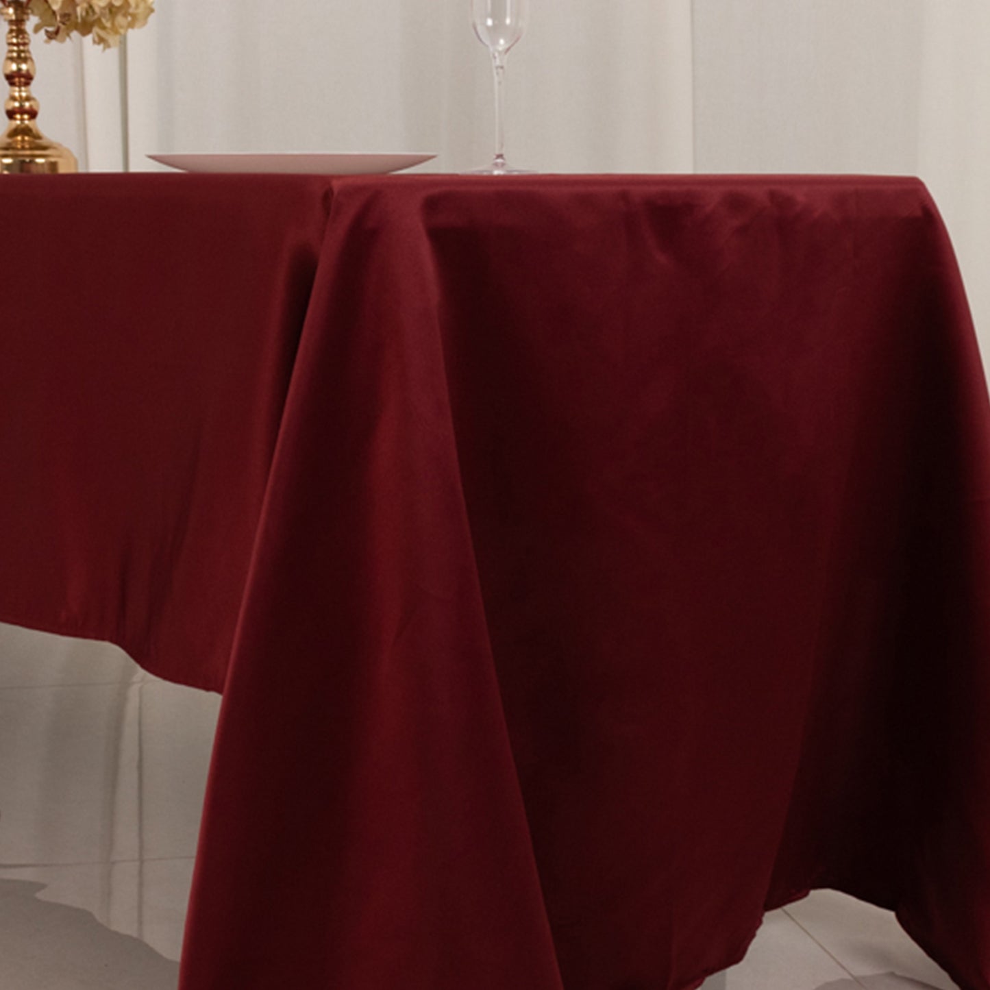 Burgundy satin rectangle tablecloth on a dining table.