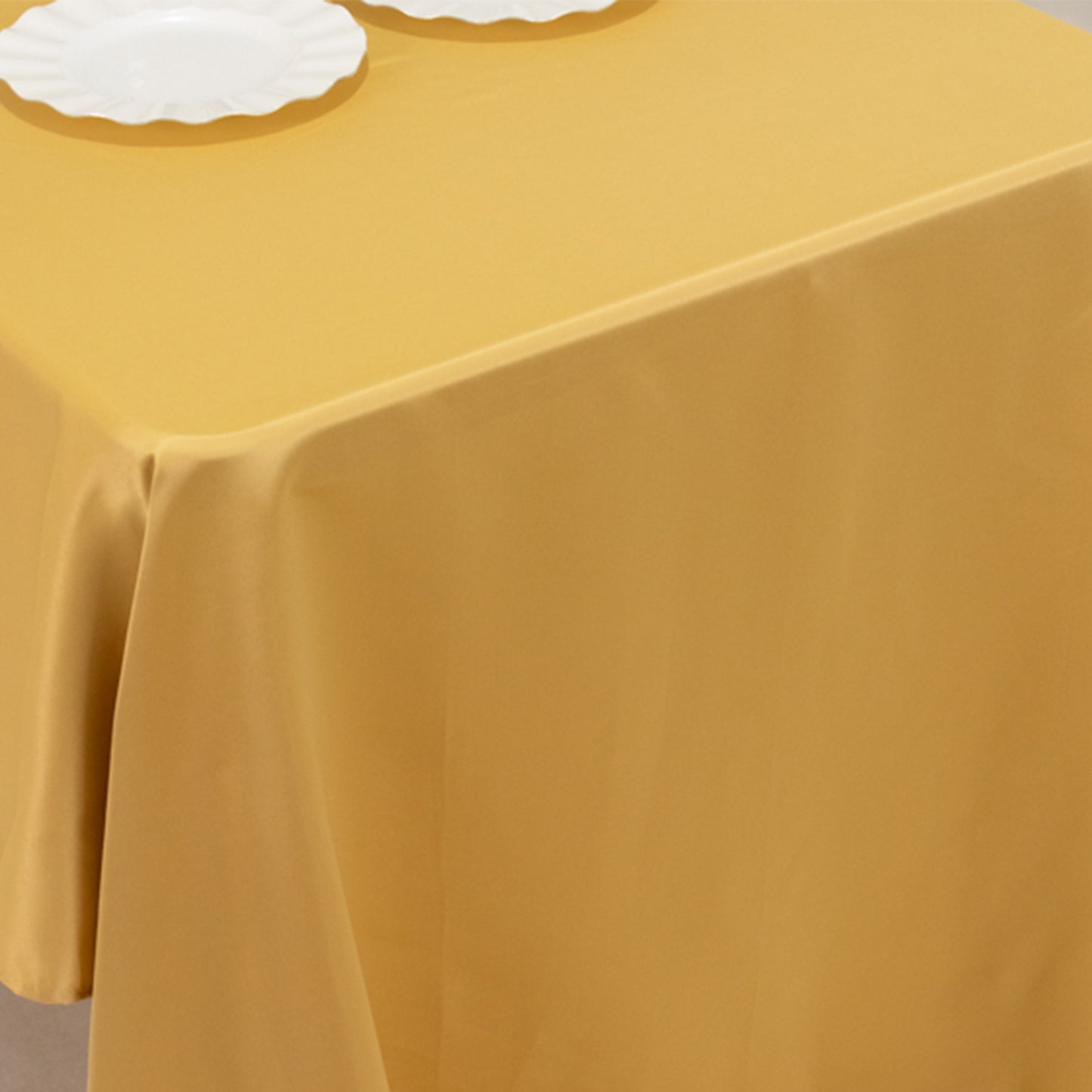 Champagne satin rectangle tablecloth on a table with white plates.