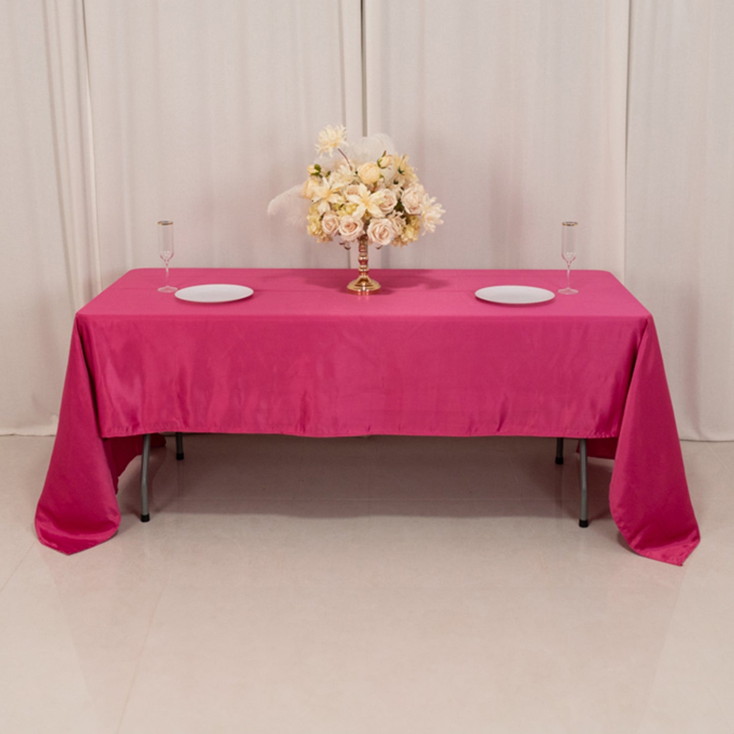 Fuchsia satin rectangle tablecloth on a table with floral centerpiece.