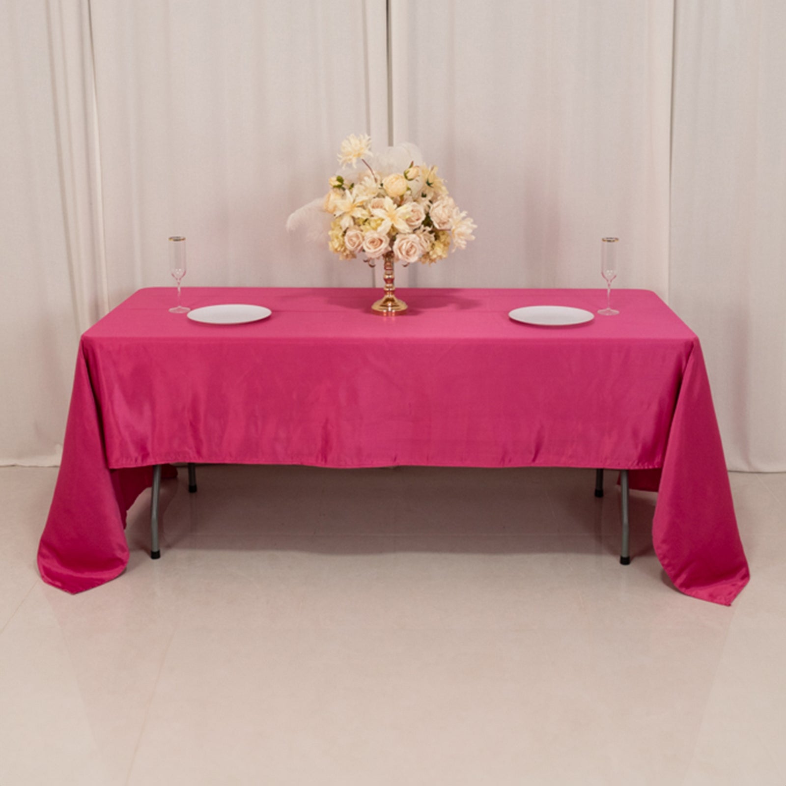 Fuchsia satin rectangle tablecloth on a table with floral centerpiece.