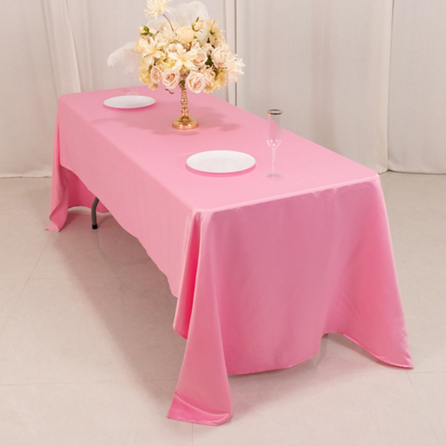 Pink satin tablecloth on a dining table with floral centerpiece.