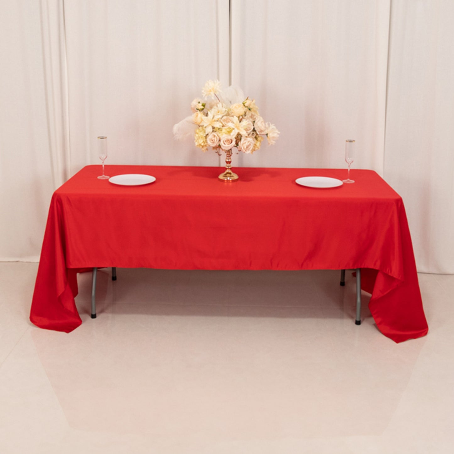 Red satin rectangle tablecloth on a table with floral centerpiece.