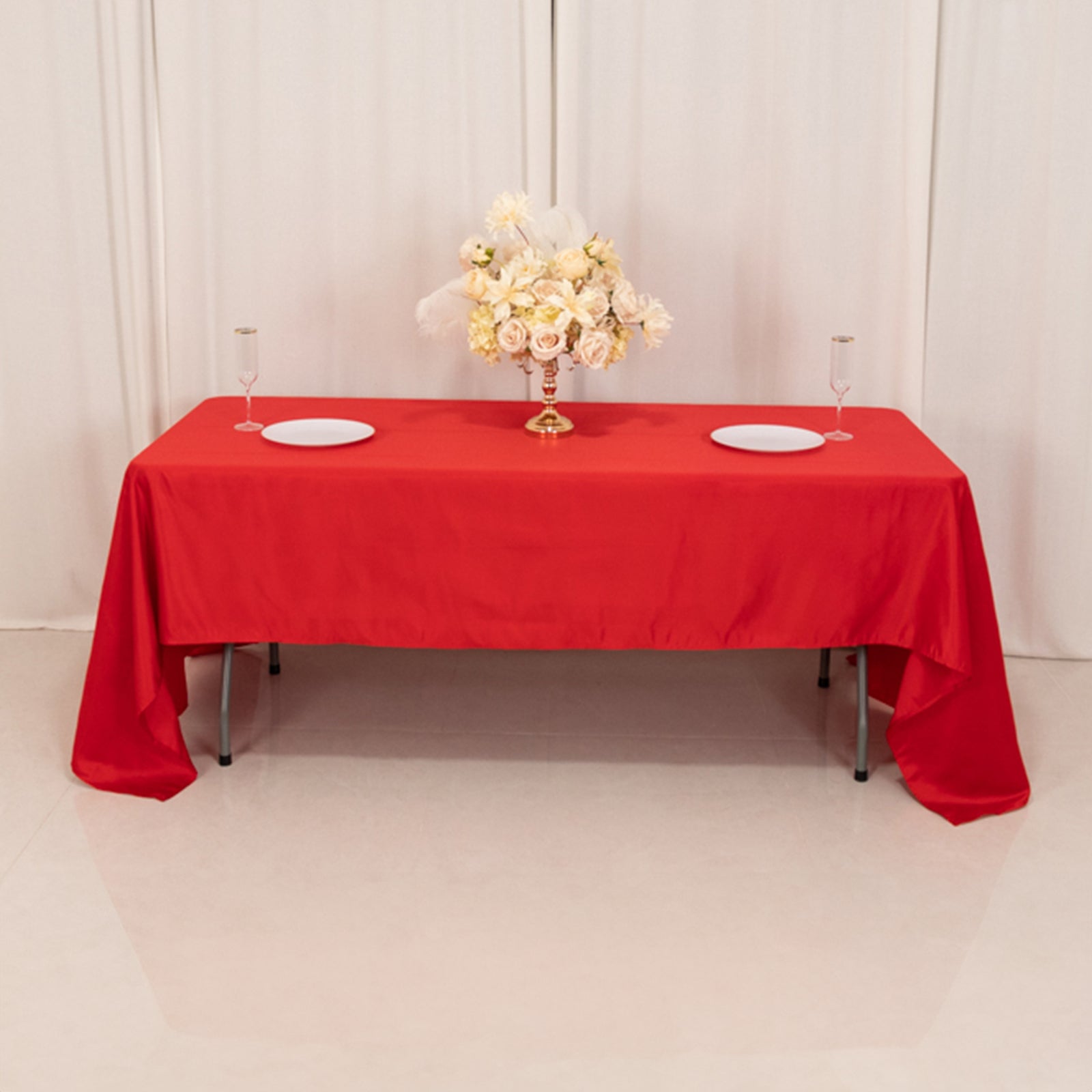 Red satin rectangle tablecloth on a table with floral centerpiece.