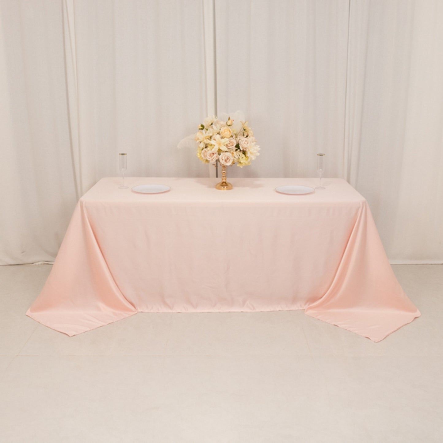 Blush satin tablecloth draping elegantly over a 6-foot table.