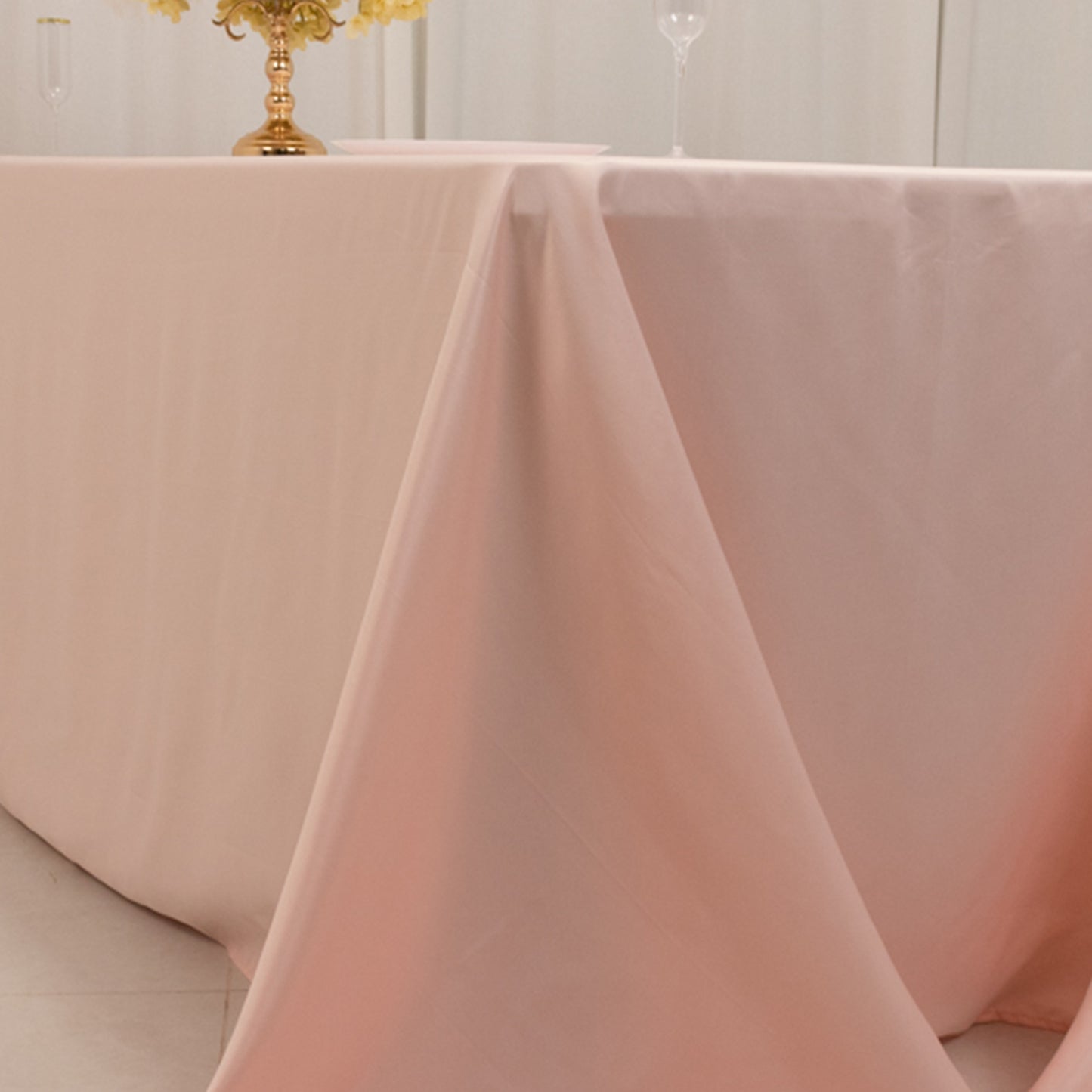 Blush satin tablecloth draping elegantly on an 8-foot table.