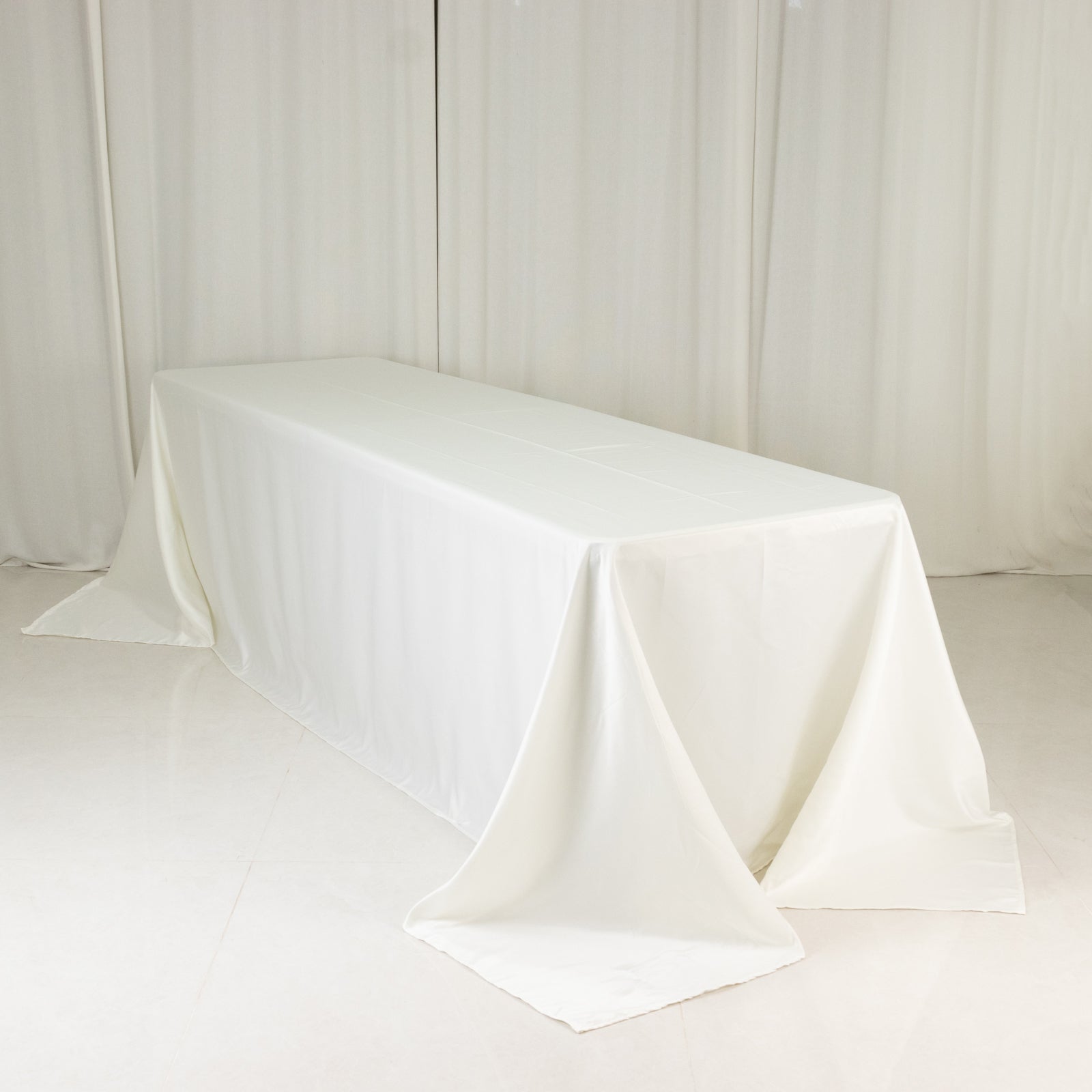 Ivory seamless satin tablecloth for 8-foot table with floor-length drop.