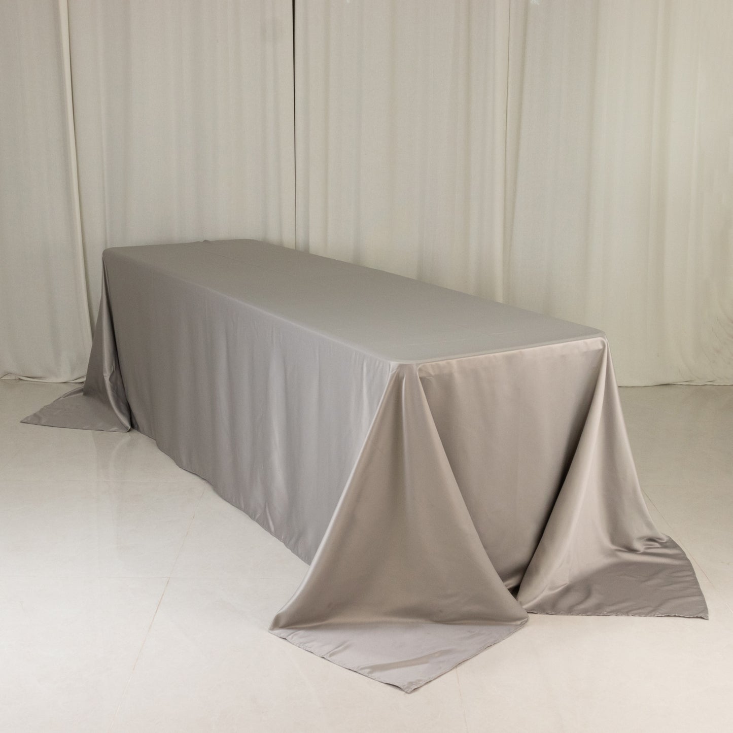 Silver seamless satin tablecloth for 8-foot table with floor-length drop.
