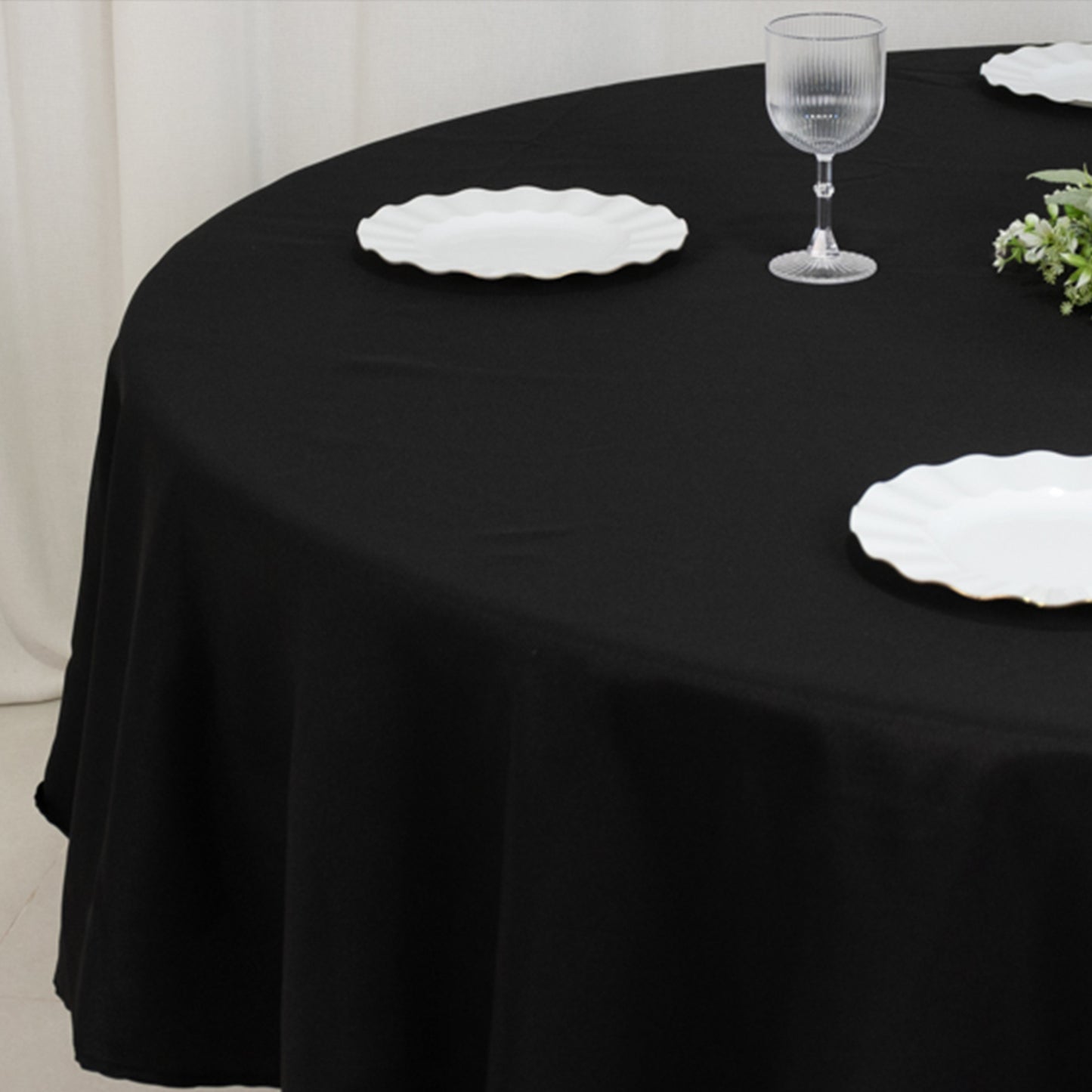 Black fire retardant round tablecloth on a dining table with white plates.