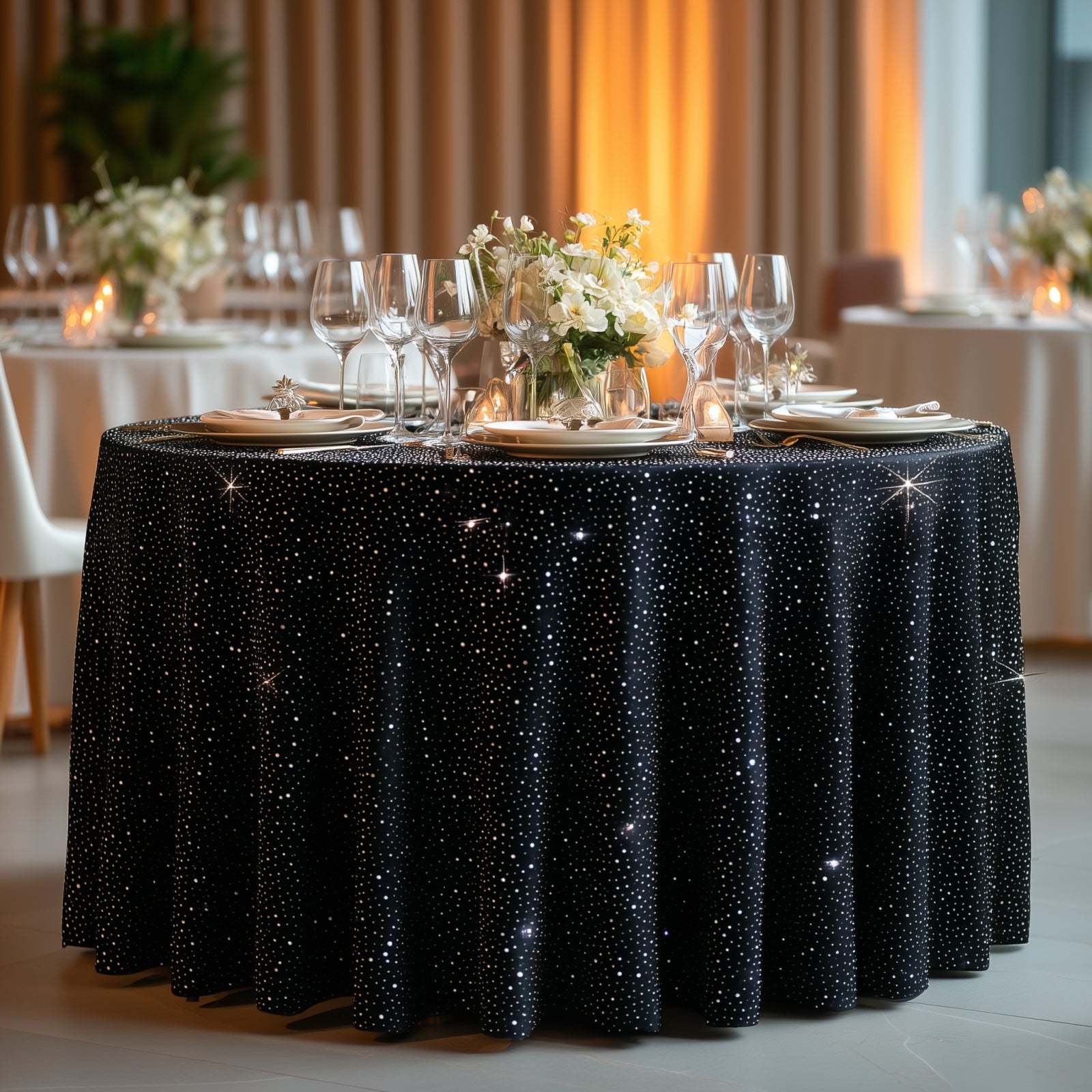 Black round tablecloth with rhinestone accents on a beautifully set dining table.