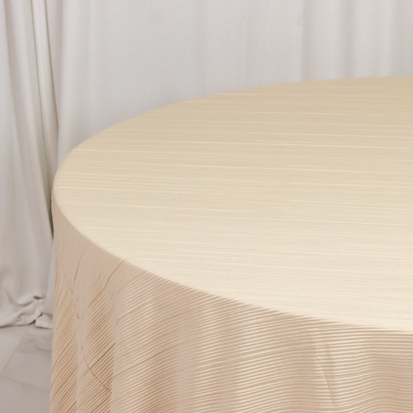 Beige accordion pleated scuba tablecloth, 120" round, wrinkle-free and stain-resistant.