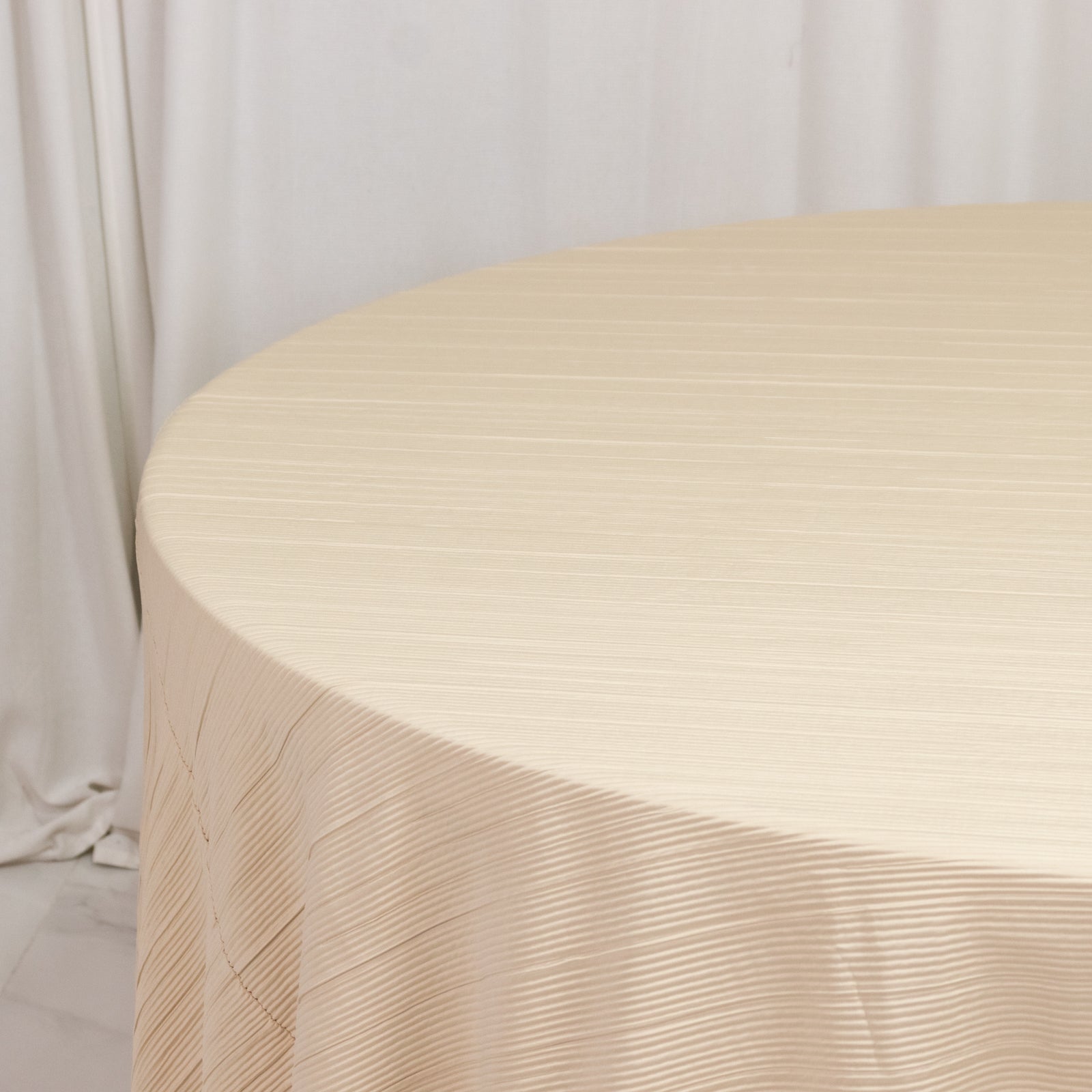 Beige accordion pleated scuba tablecloth, 120" round, wrinkle-free and stain-resistant.