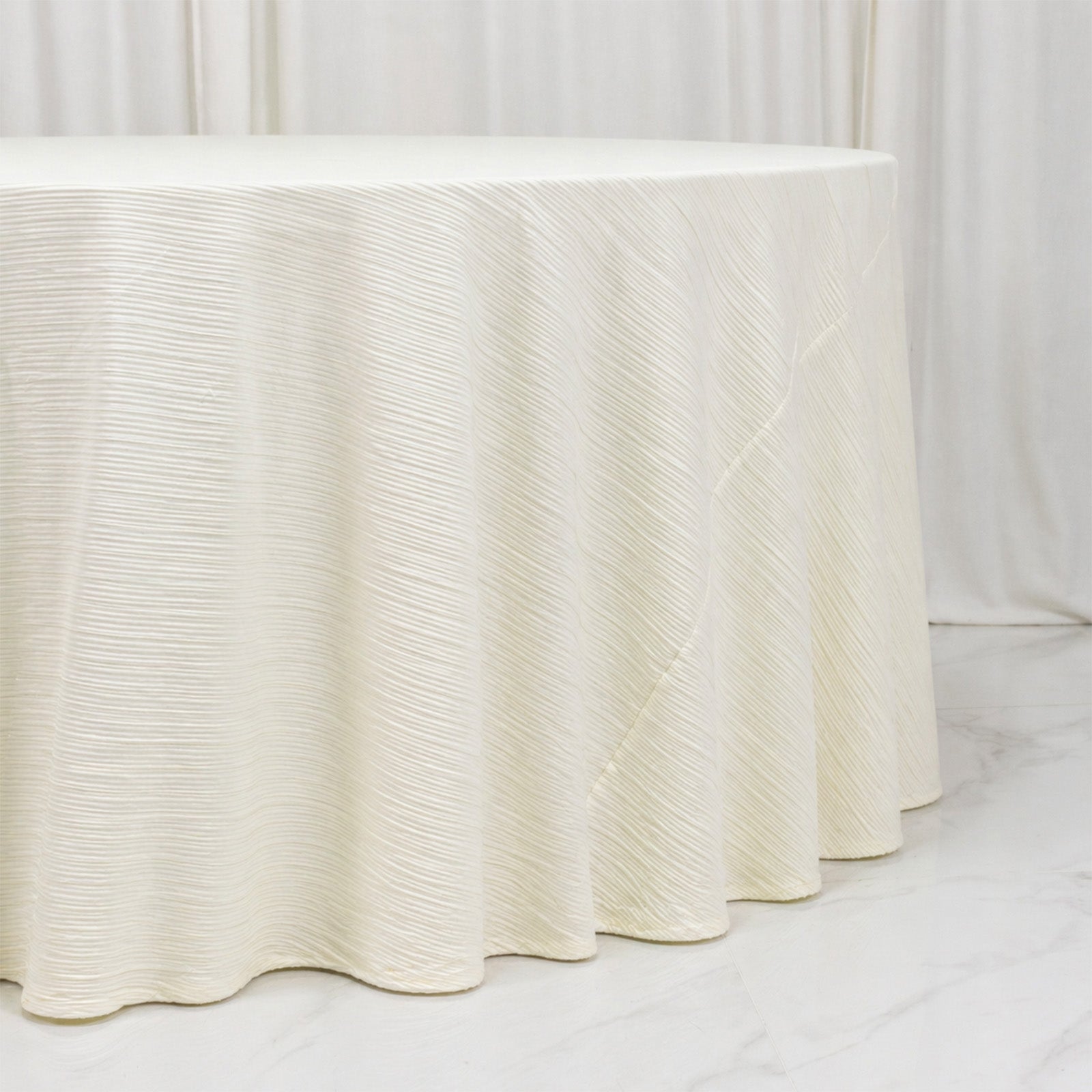 Ivory accordion pleated scuba tablecloth 120" round, wrinkle-free and stain-resistant.