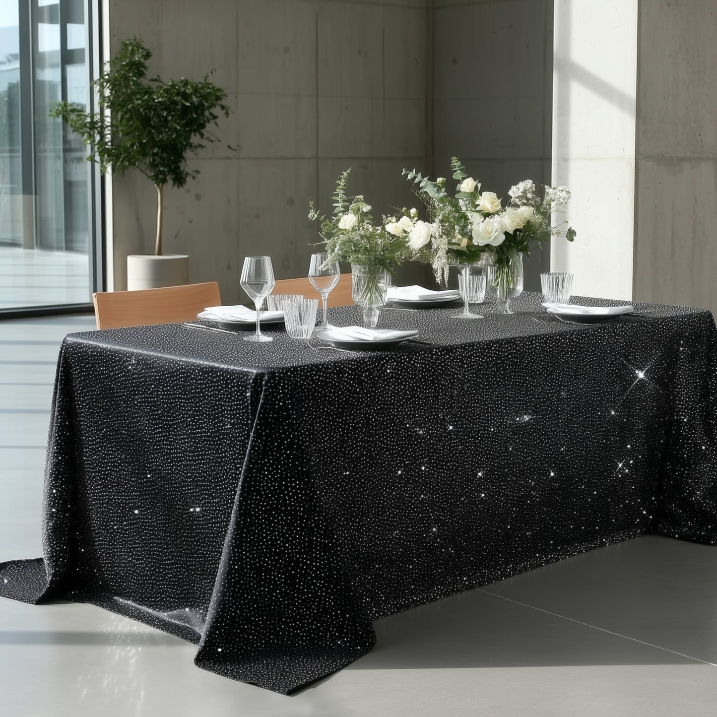 Black tablecloth with rhinestone accents on a dining table setting.
