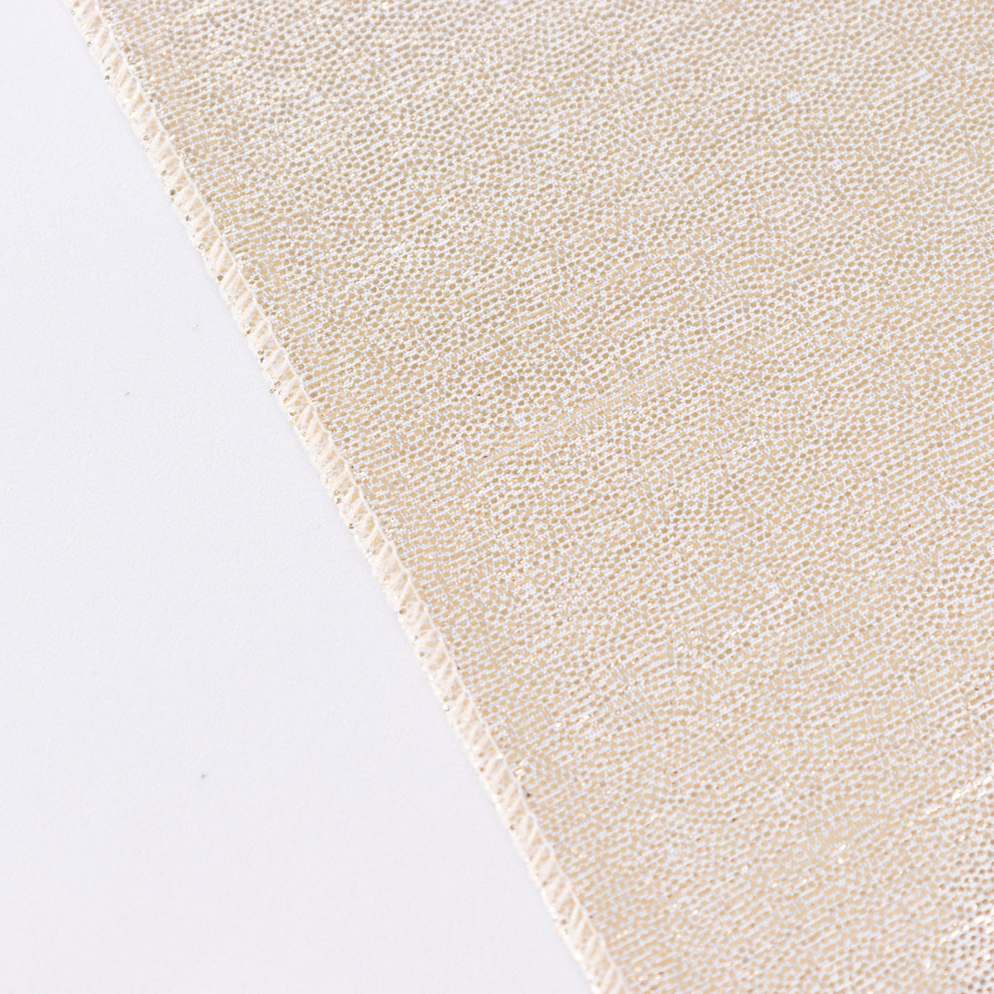 Shiny beige tablecloth with shimmer sequin dots on a white surface.
