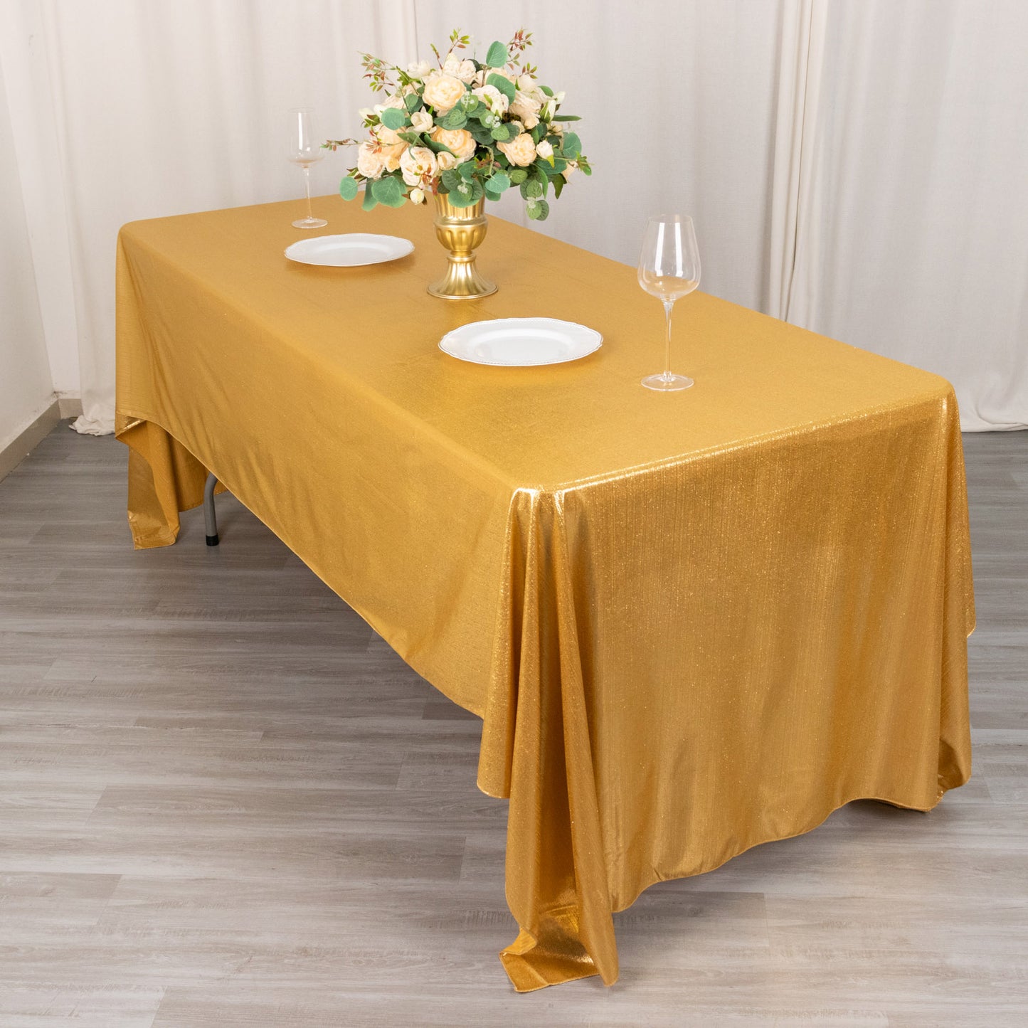 Shiny gold rectangular tablecloth with shimmer sequin dots on a table.