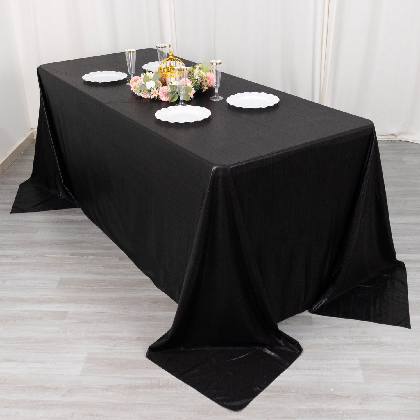 Black sequin tablecloth on a dining table with floral centerpiece and plates.