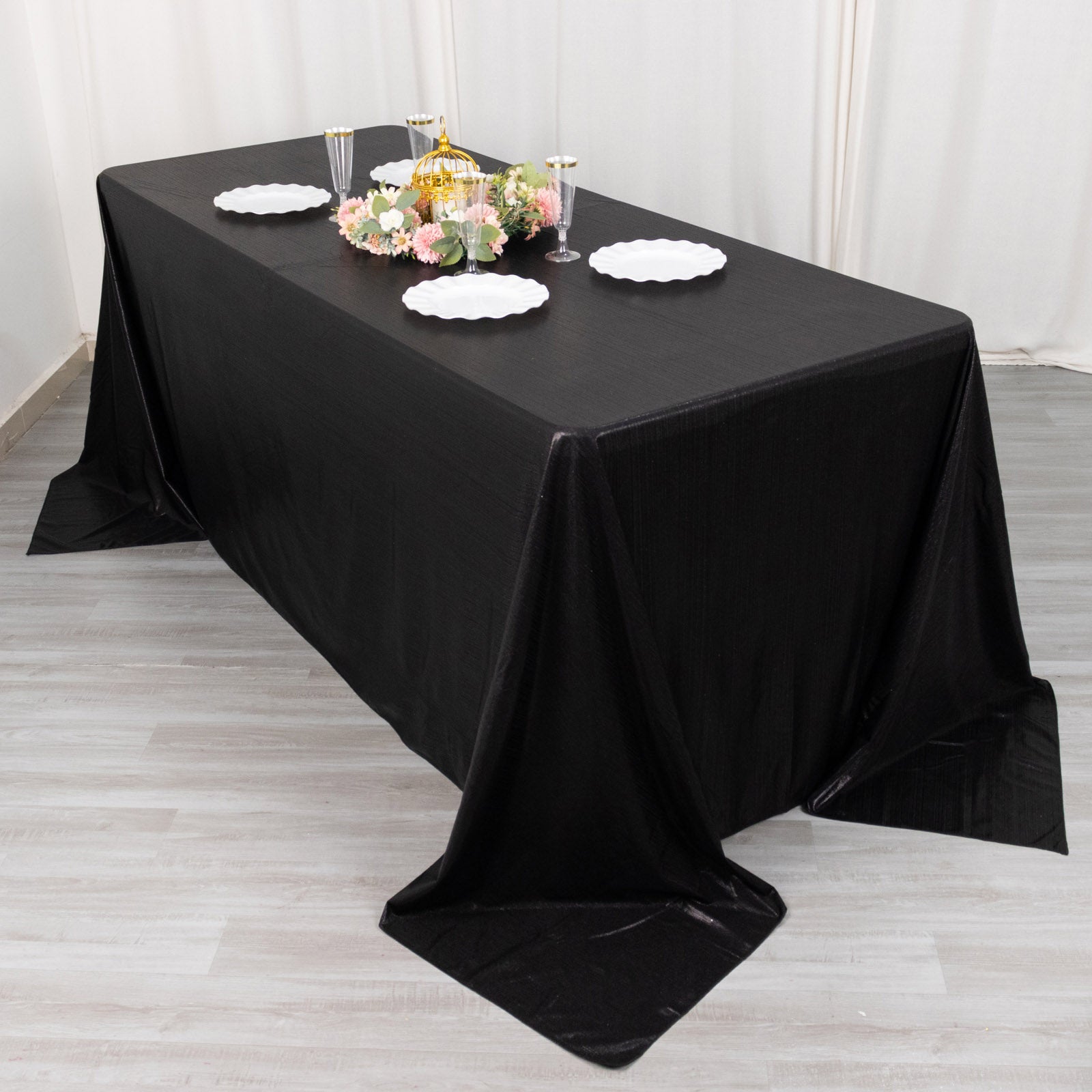 Black sequin tablecloth on a dining table with floral centerpiece and plates.