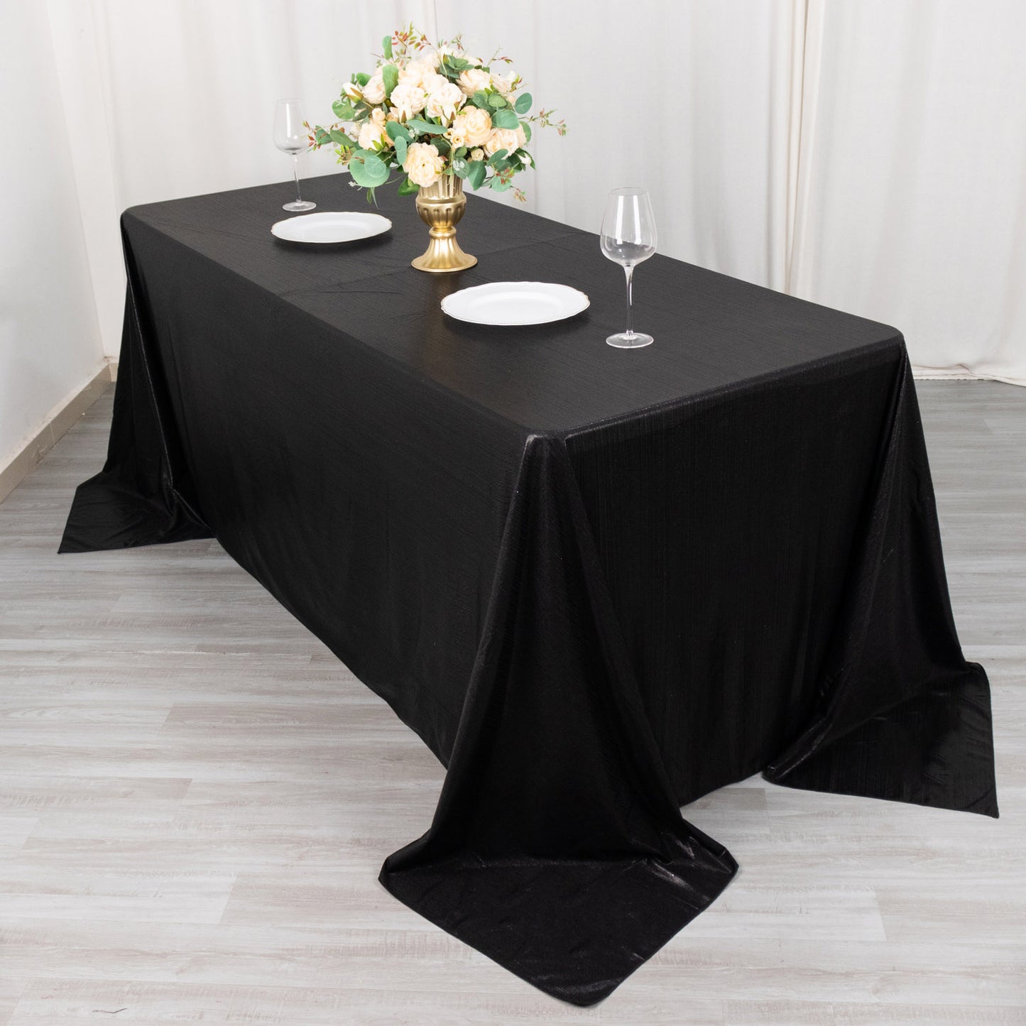 Black shimmer sequin tablecloth on a dining table with floral centerpiece.