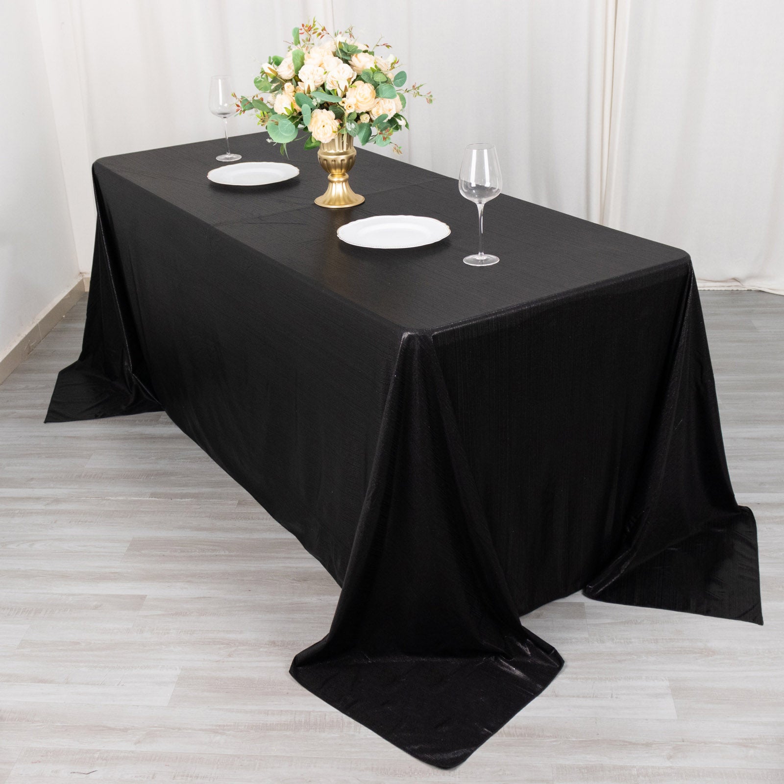 Black shimmer sequin tablecloth on a dining table with floral centerpiece.