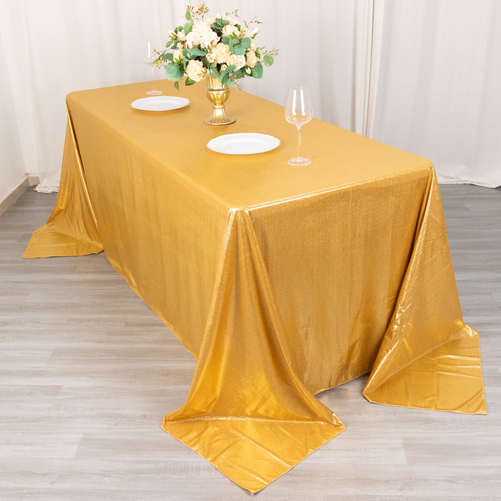 Gold shimmer sequin tablecloth on a dining table with floral centerpiece.