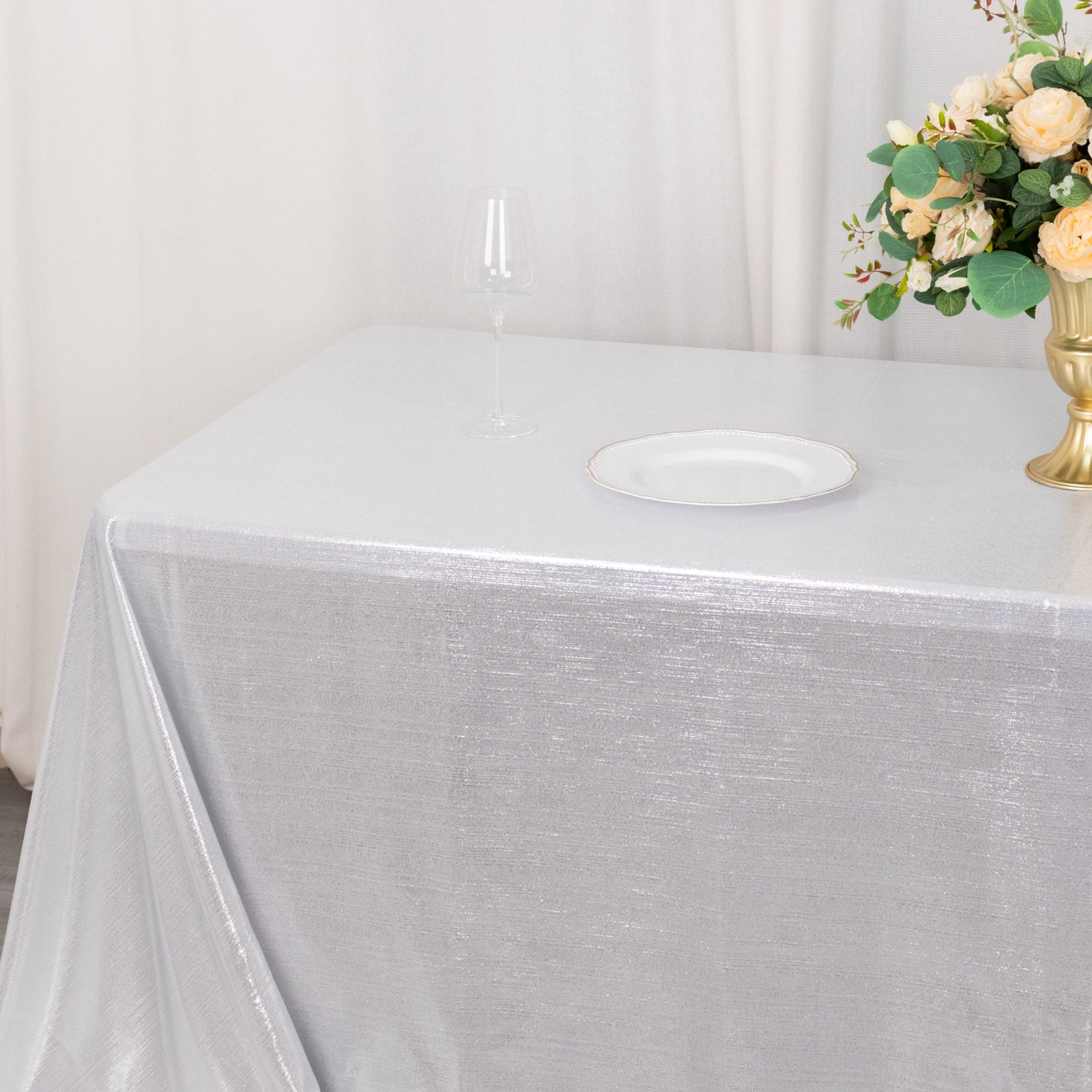 Silver shimmer sequin tablecloth on a table with floral arrangement.