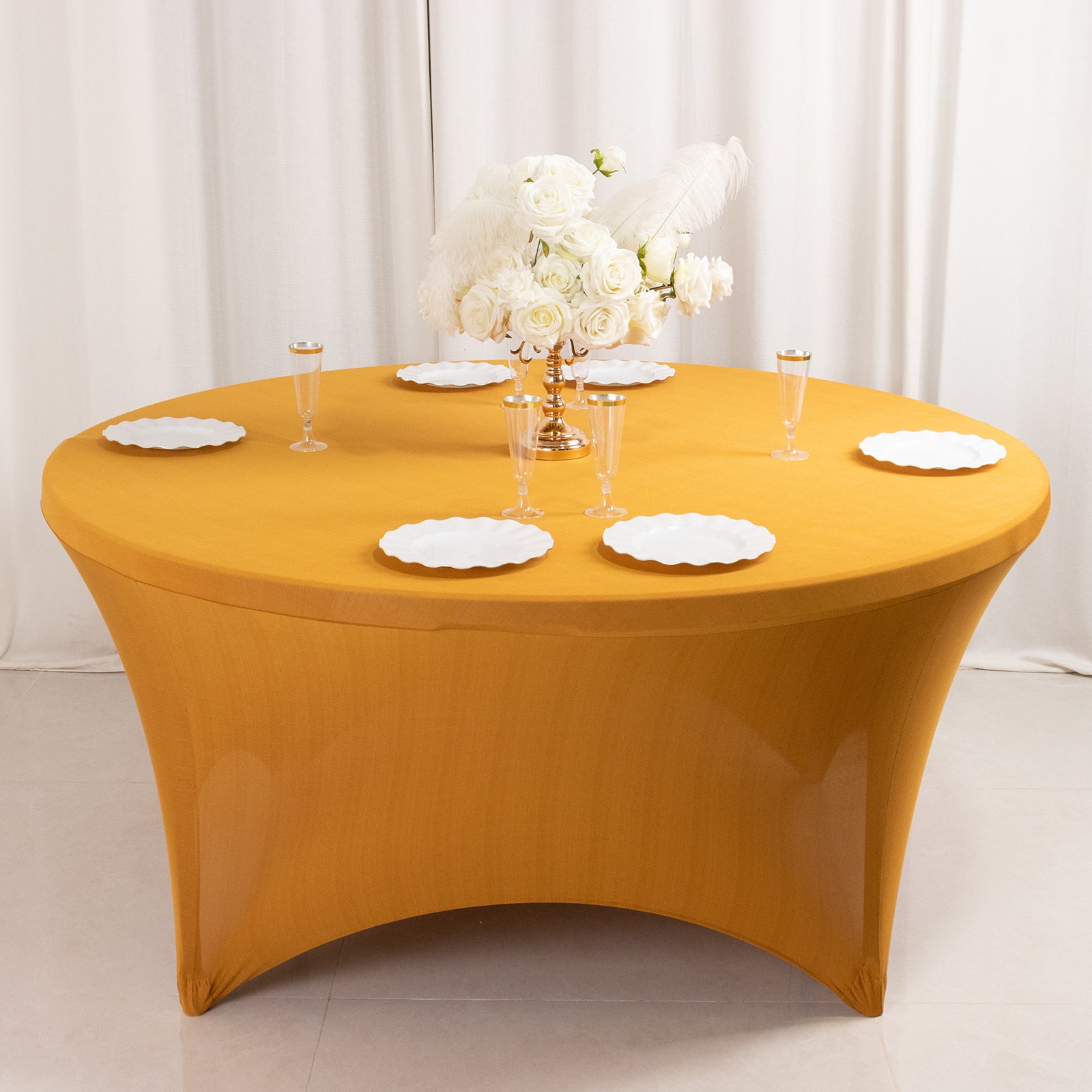 Gold fitted round tablecloth for 5-foot tables with plates and decor.