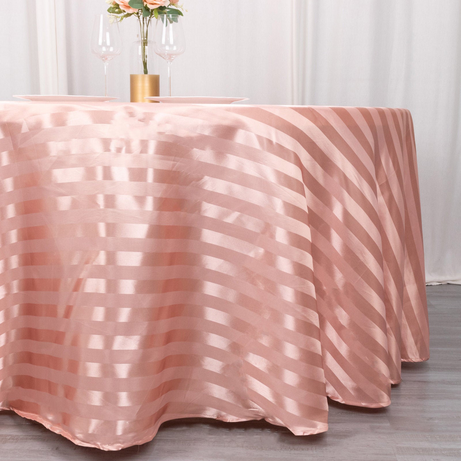 Dusty rose satin stripe round tablecloth on a table.