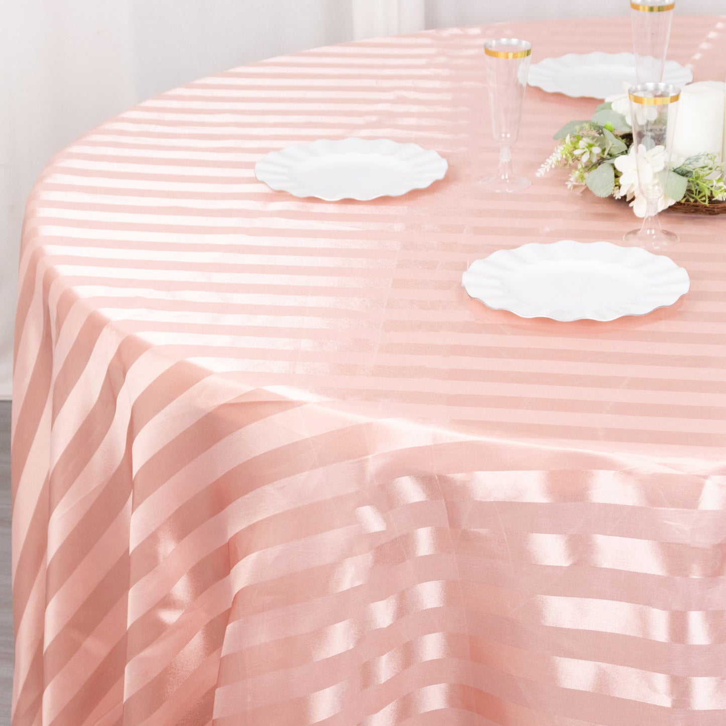 Dusty rose satin stripe seamless round tablecloth on a dining table.