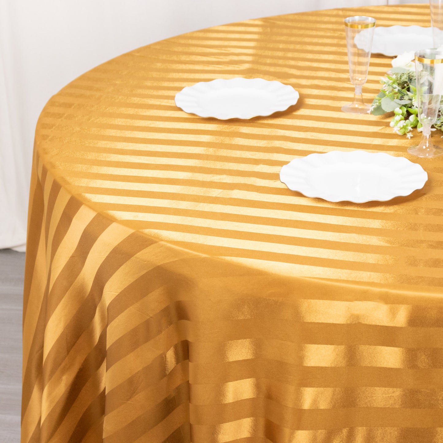 Gold satin stripe seamless round tablecloth on a table.