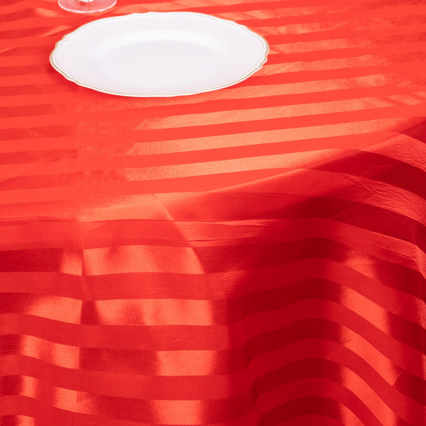 Red satin stripe round tablecloth on a dining table.
