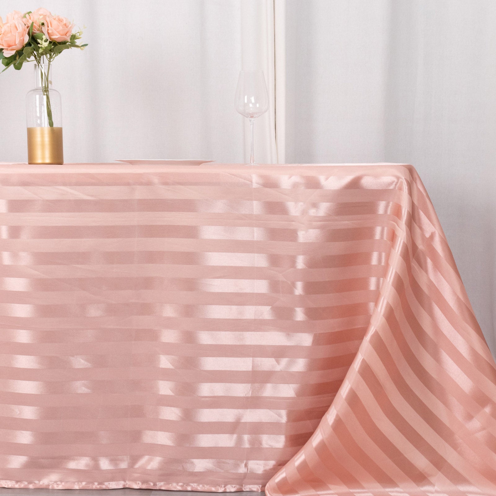 Dusty rose satin stripe tablecloth on a table with flowers.