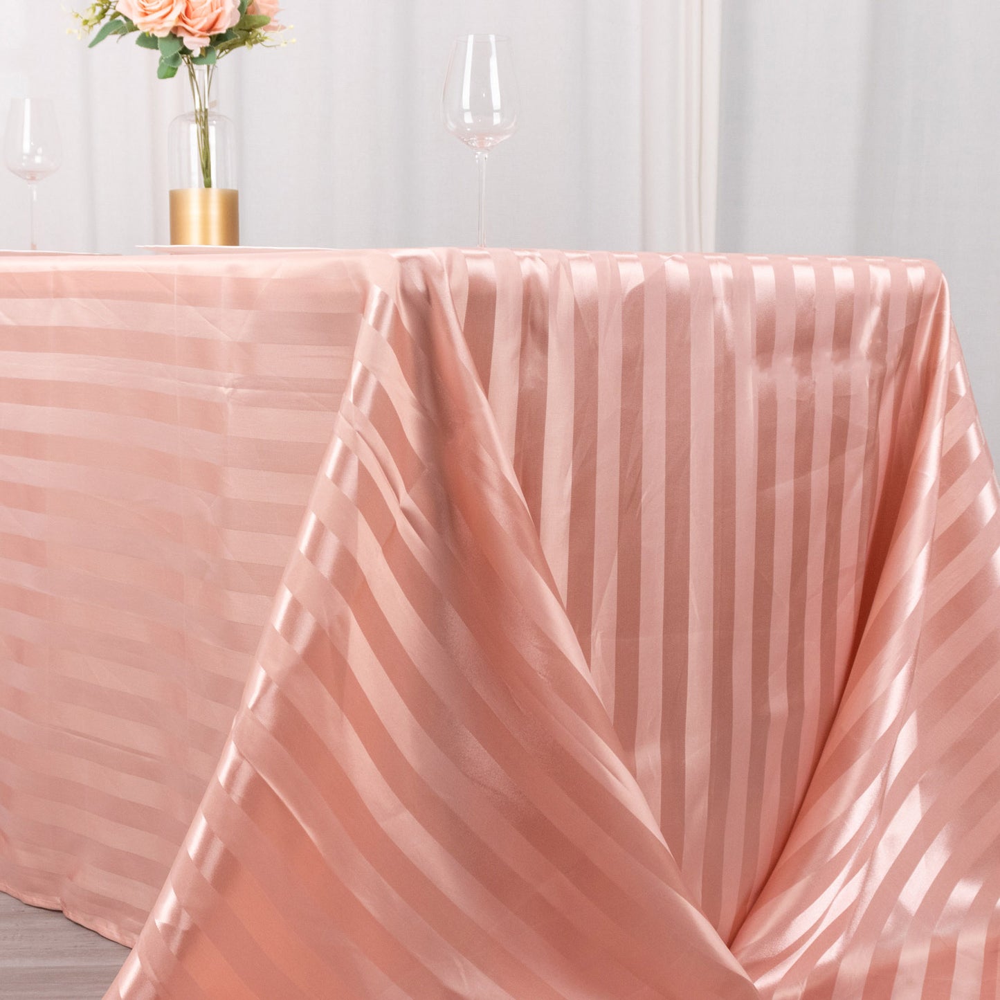 Dusty rose satin stripe tablecloth draped elegantly on a table.