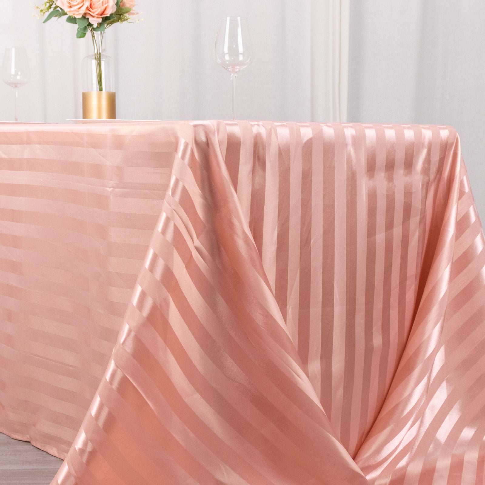 Dusty rose satin stripe tablecloth draped elegantly on a table.